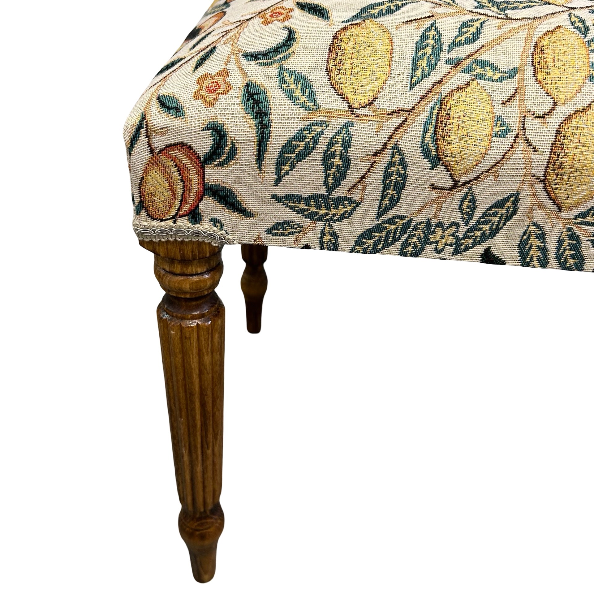 Decorative bench with floral and fruit patterned fabric on a white background.