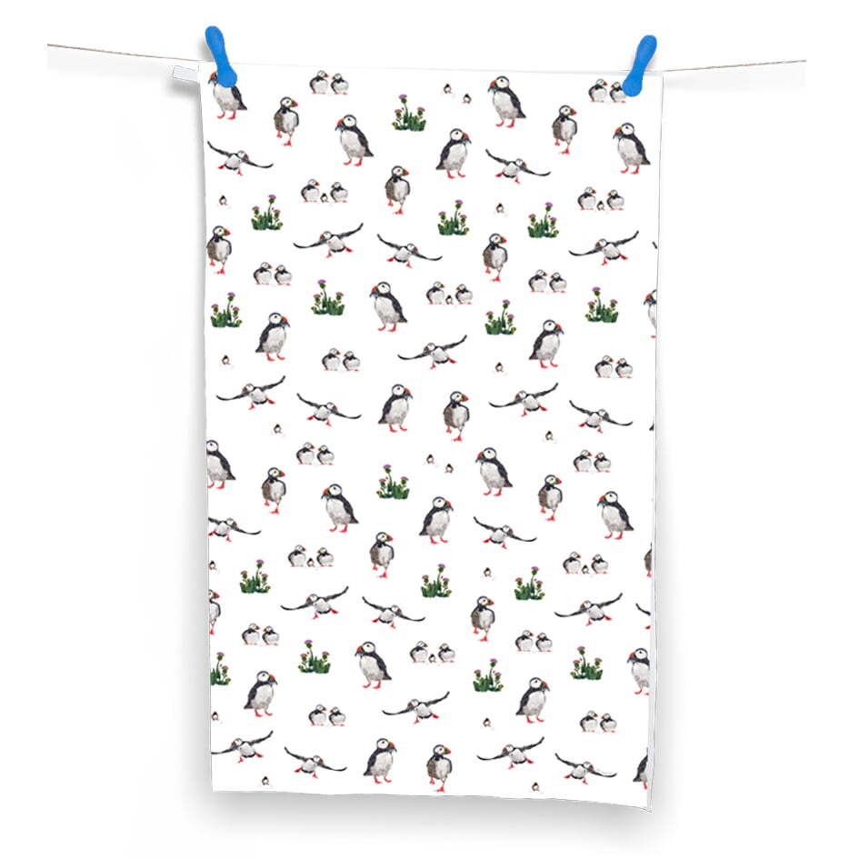 This white tea towel illustrates multiple puffins, flying and standing.