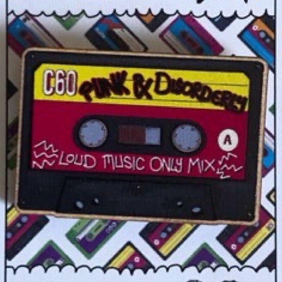 Cassette tape-shaped pin badge with 'Punk & Disorderly' text on a colorful background.