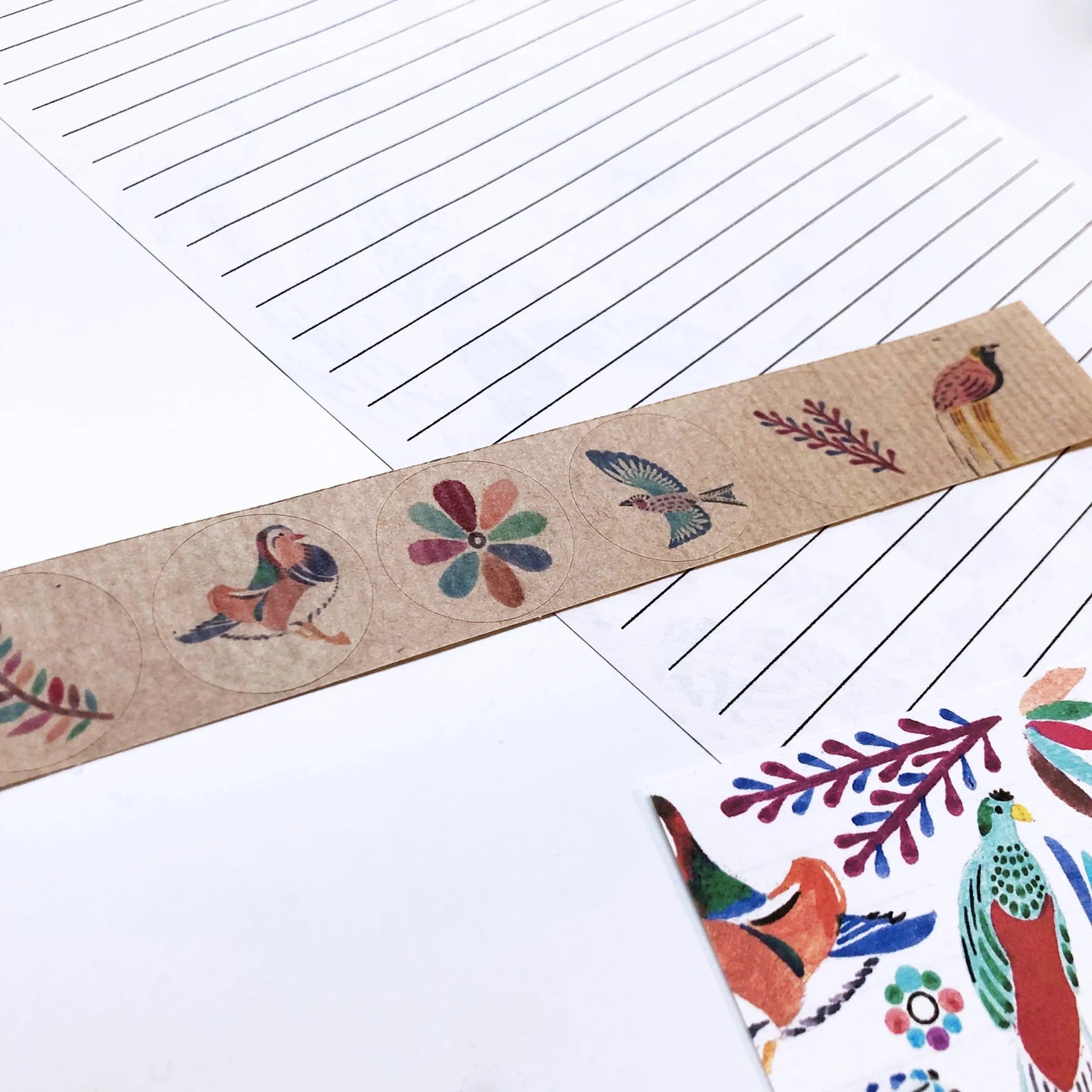 Decorative strip with bird and flower designs on a lined paper background.