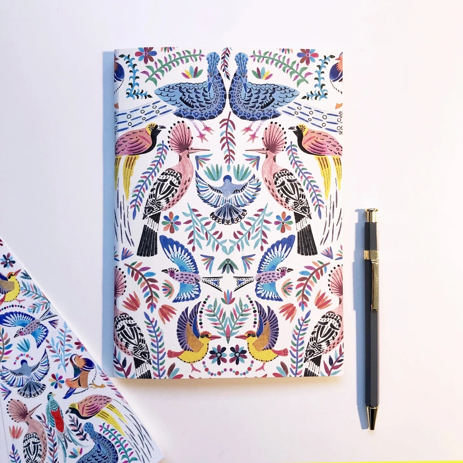Notebook with a colorful bird pattern on a white background.
