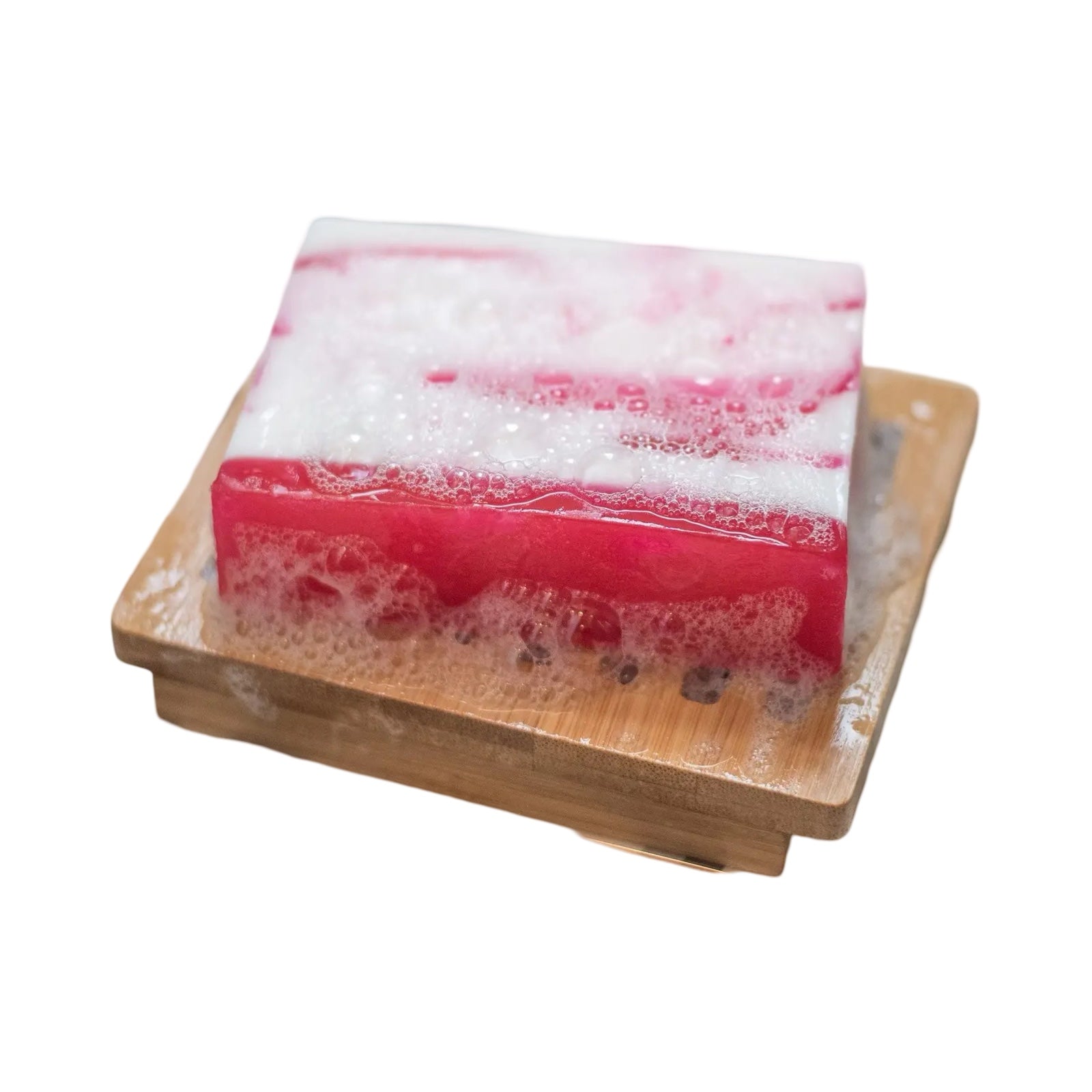 A bar of pink and white raspberry ripple soap sitting on a wooden soap dish.