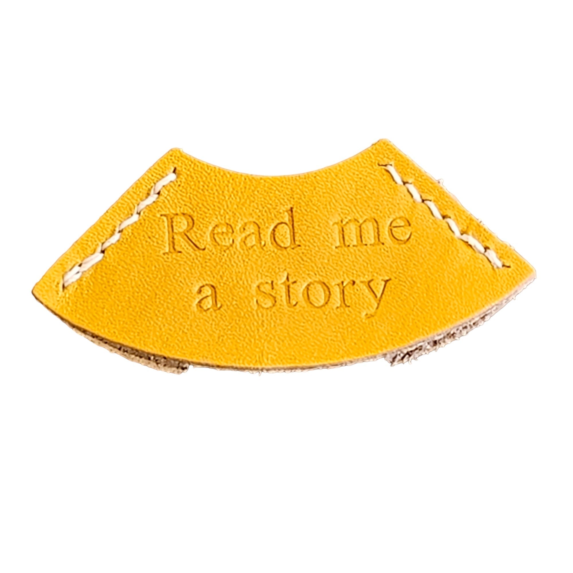 A yellow leather bookmark with the embossed text 'READ ME A STORY'.