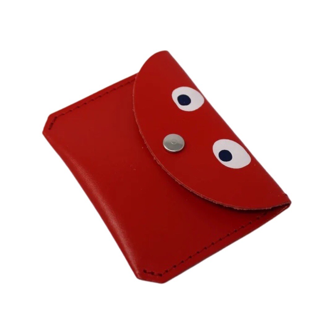 A red leather coin purse with googly eyes and a gold fastening in the centre.