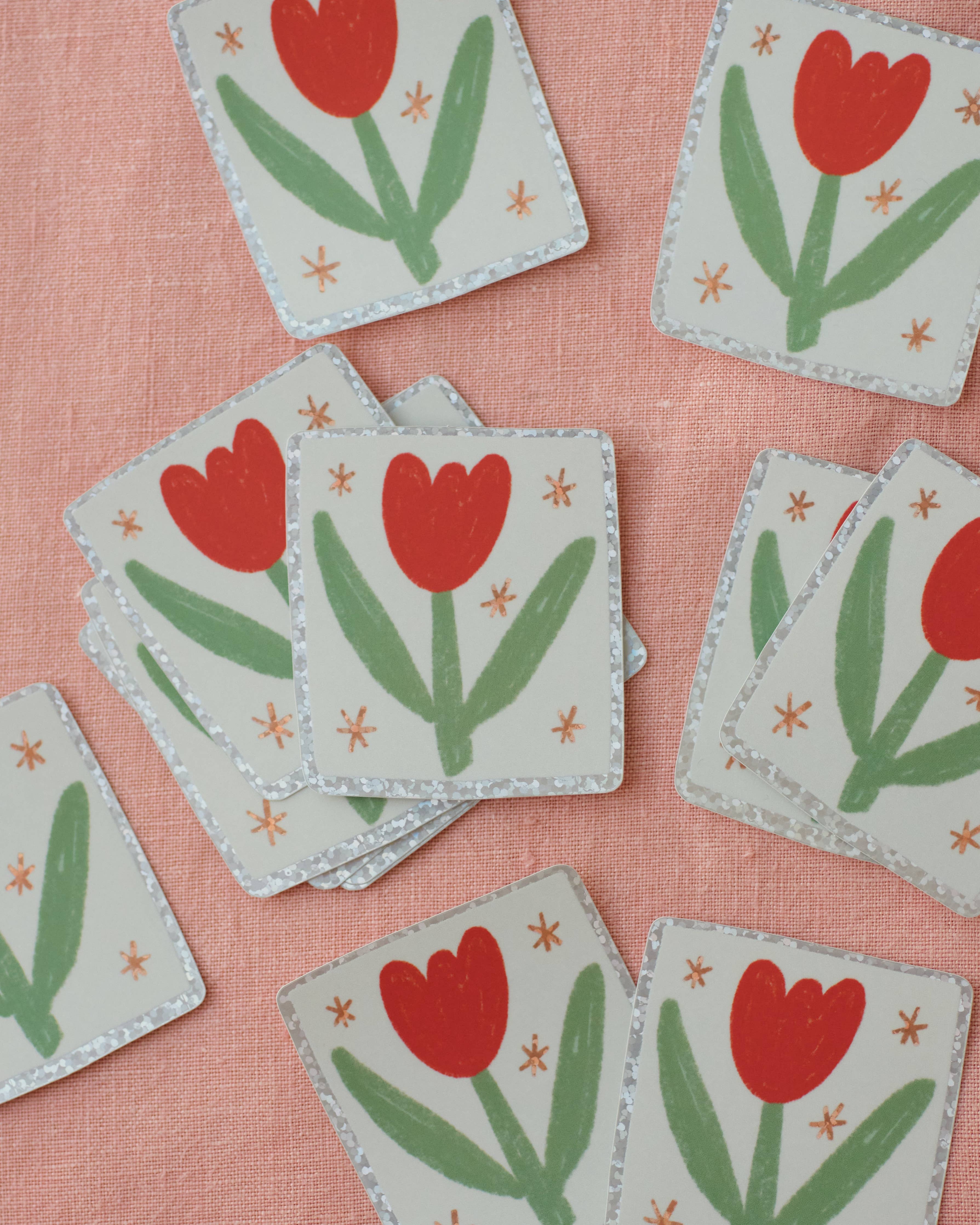 Square stickers with red tulip designs on a pink fabric background.