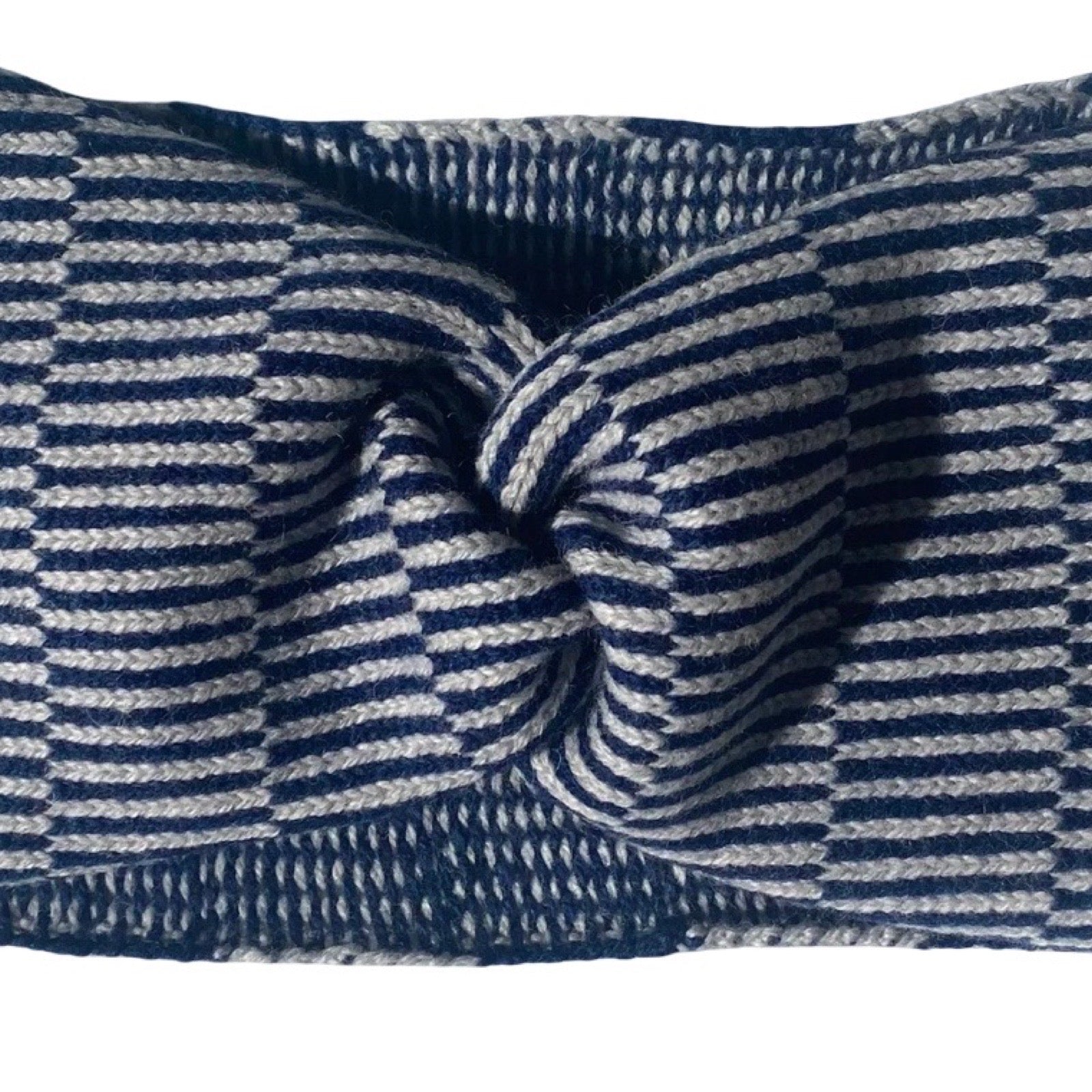 A close-up of a knotted fabric headband with a woven pattern in navy blue and grey.