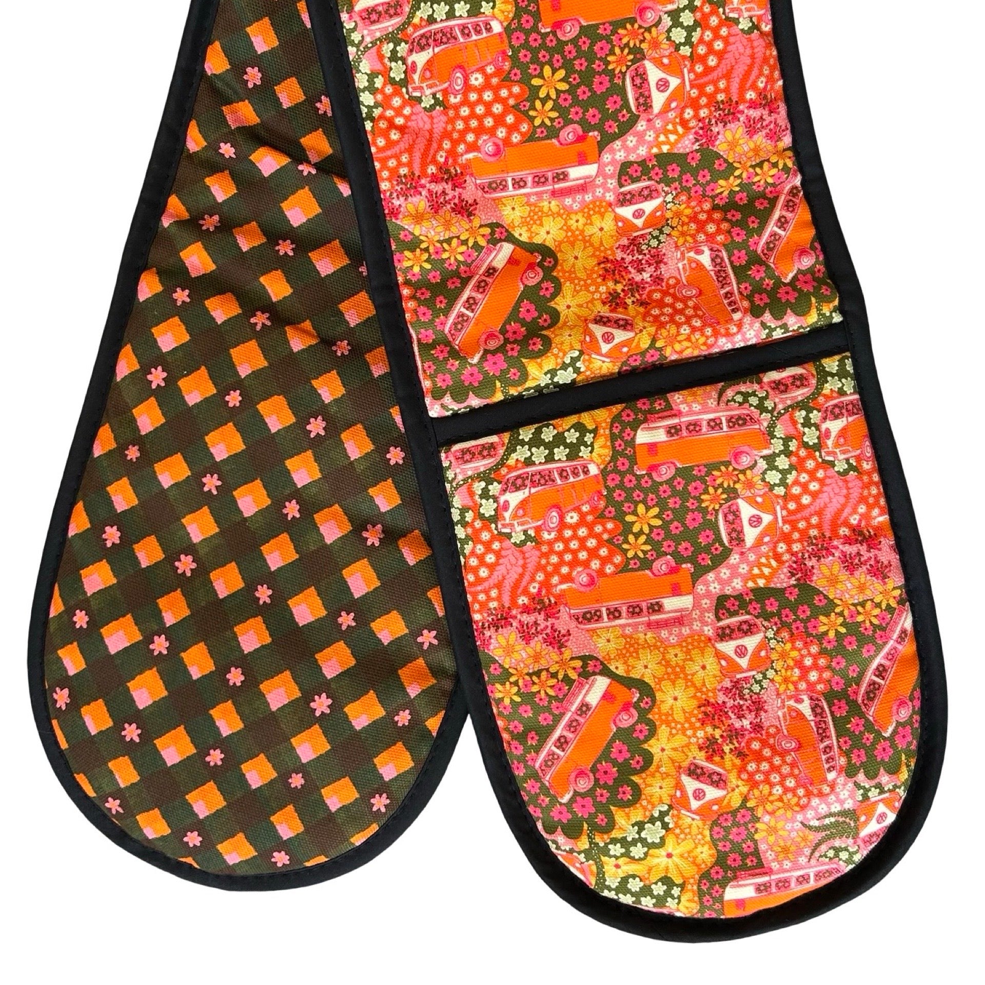 Oven gloves with a repeat pattern illustration of an orange and cream VW campervan against a floral backdrop on the front and a checked pink, orange, green and black patterned reverse.