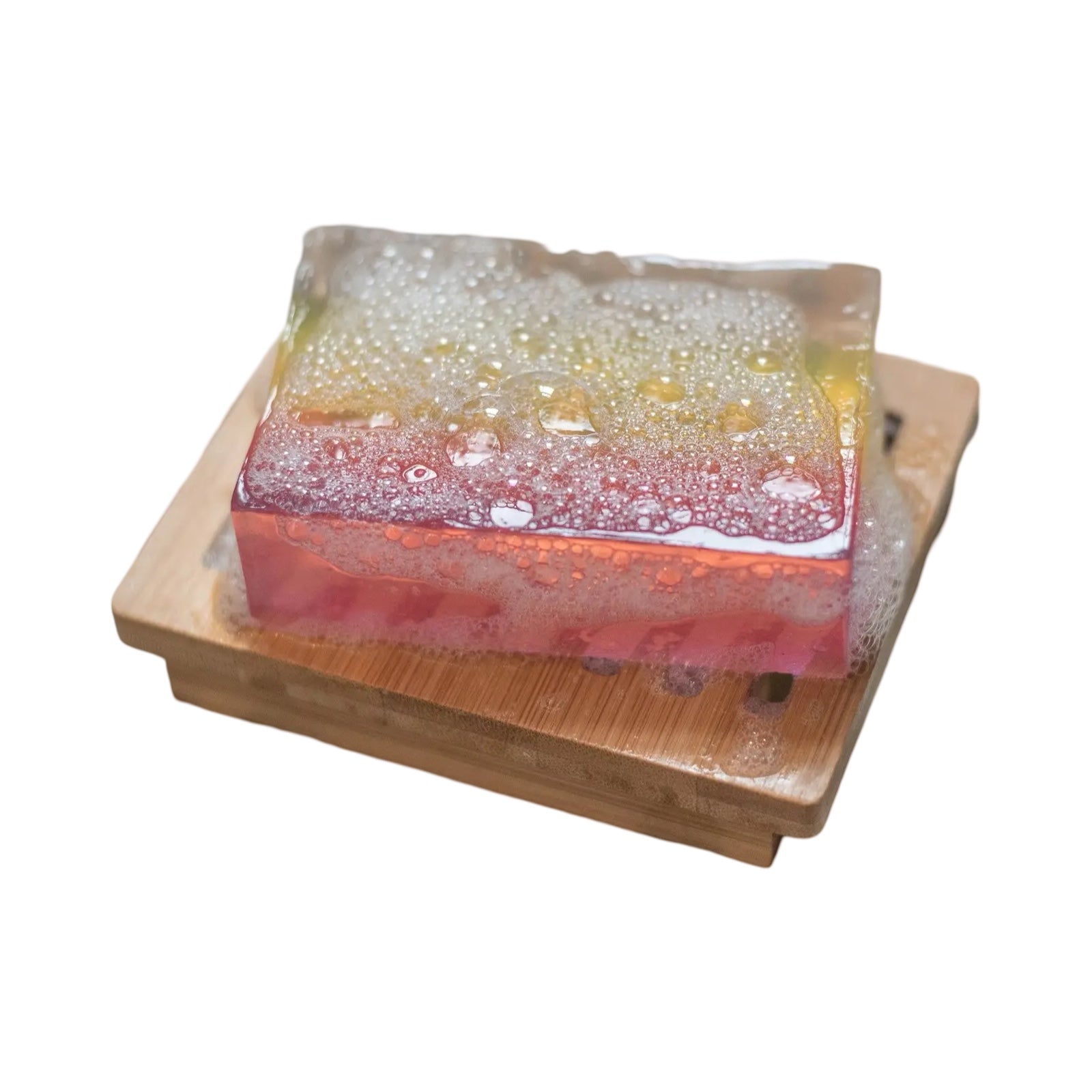 A bar of white, yellow and pink rhubarb and ginger soap sitting on a wooden soap dish.