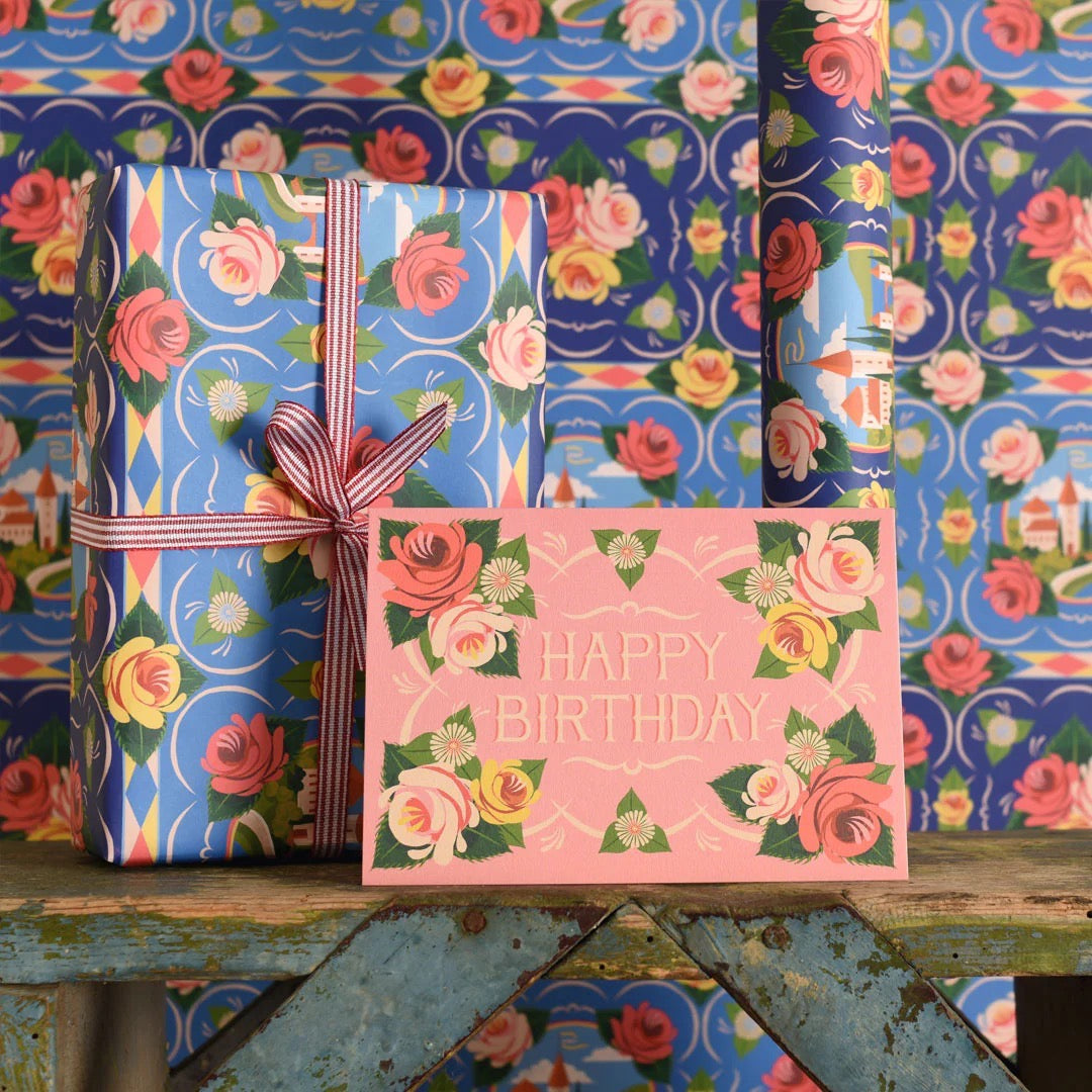 Gift wrapped in floral paper with a 'Happy Birthday' card on a colourful background.