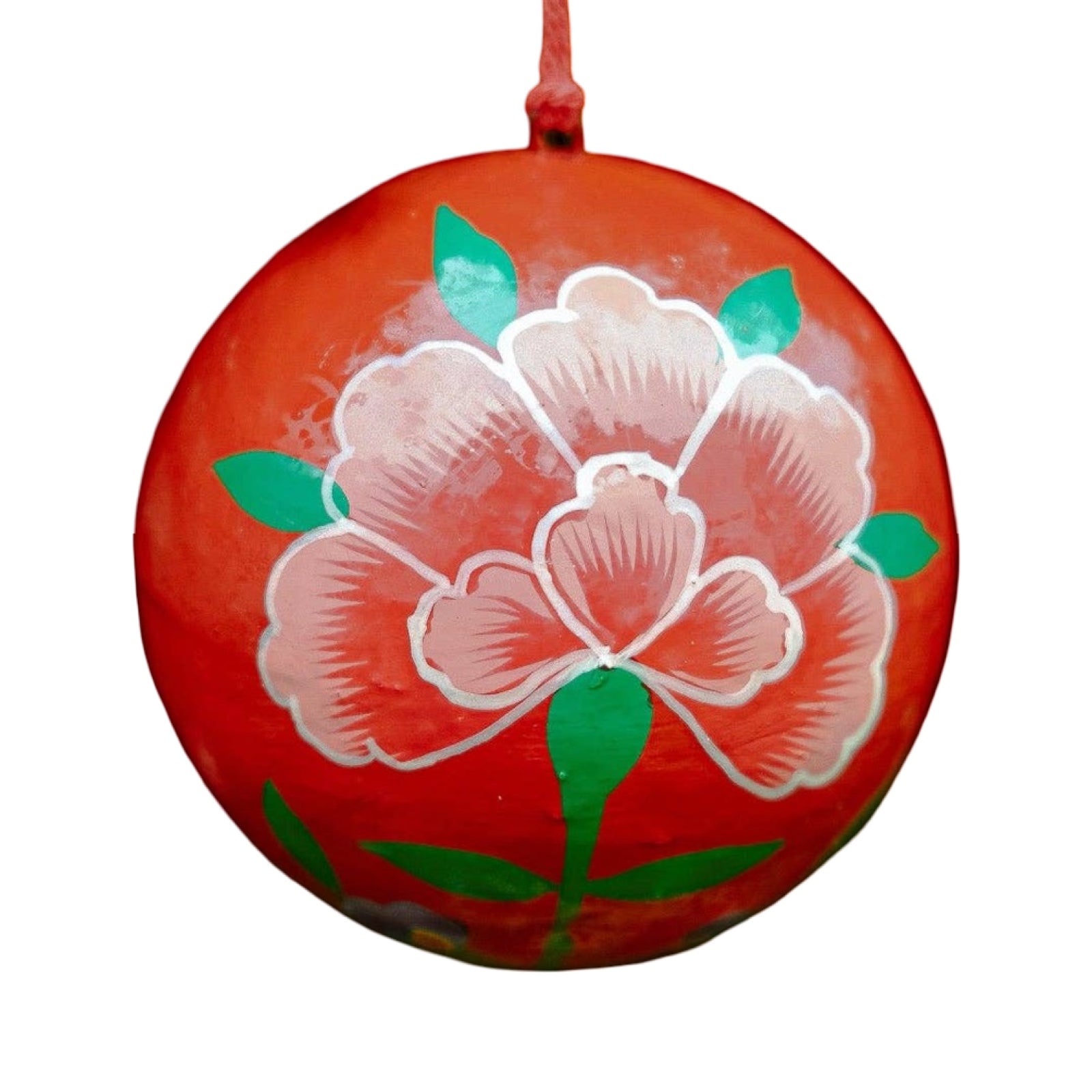 A round papier mache bauble in red with a red, green and white floral design.