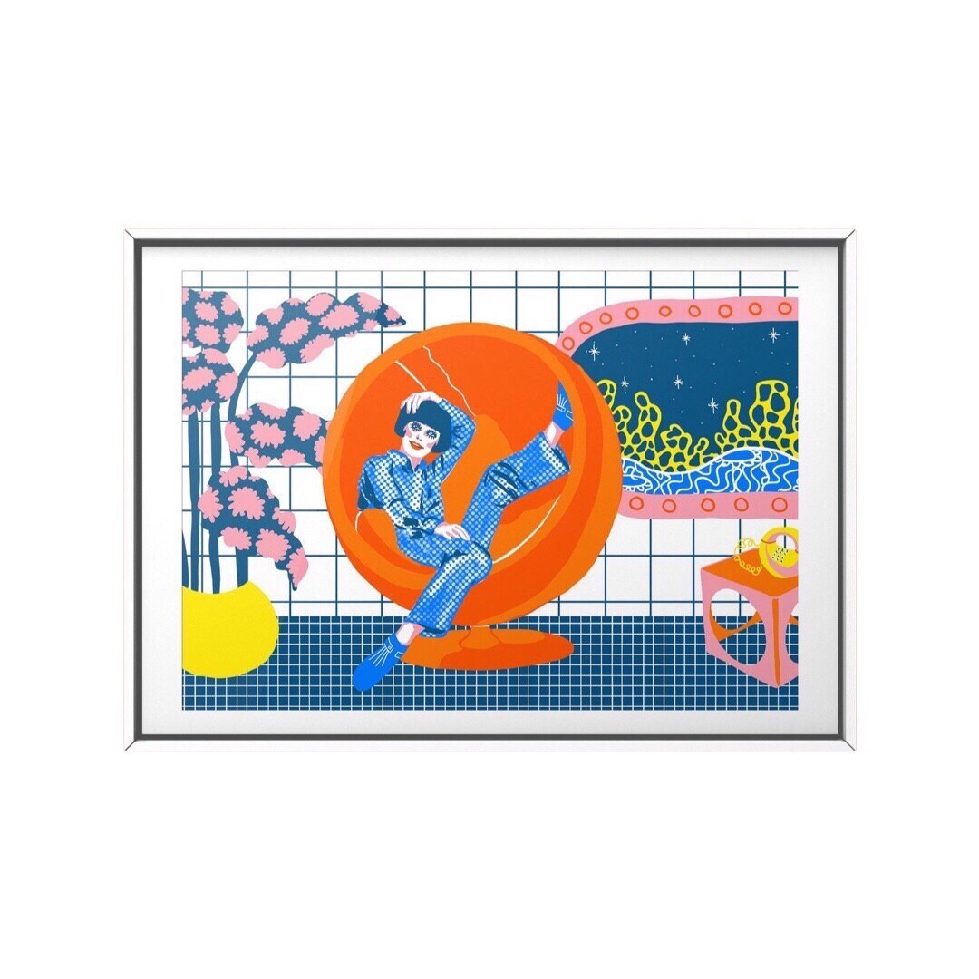 Framed retro-inspired art print featuring a lady in an underwater room wearing a fabulous blue jumpsuit relaxing in an orange bubble chair.