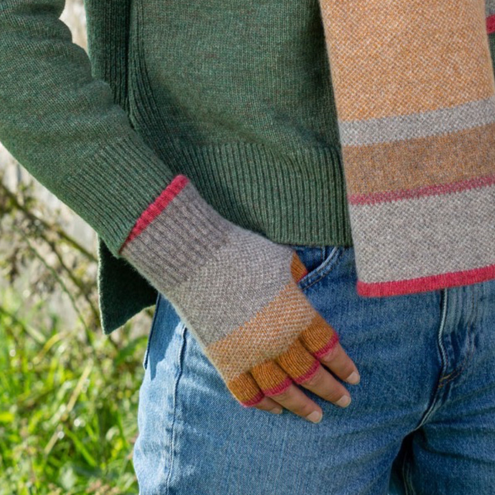 Person wearing colourful fingerless gloves outdoors.