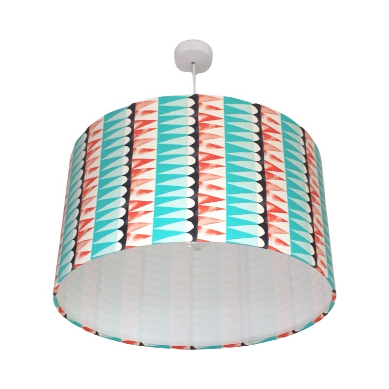 Drum lampshade with rows of turquoise, burnt orange and black shapes against a cream background.