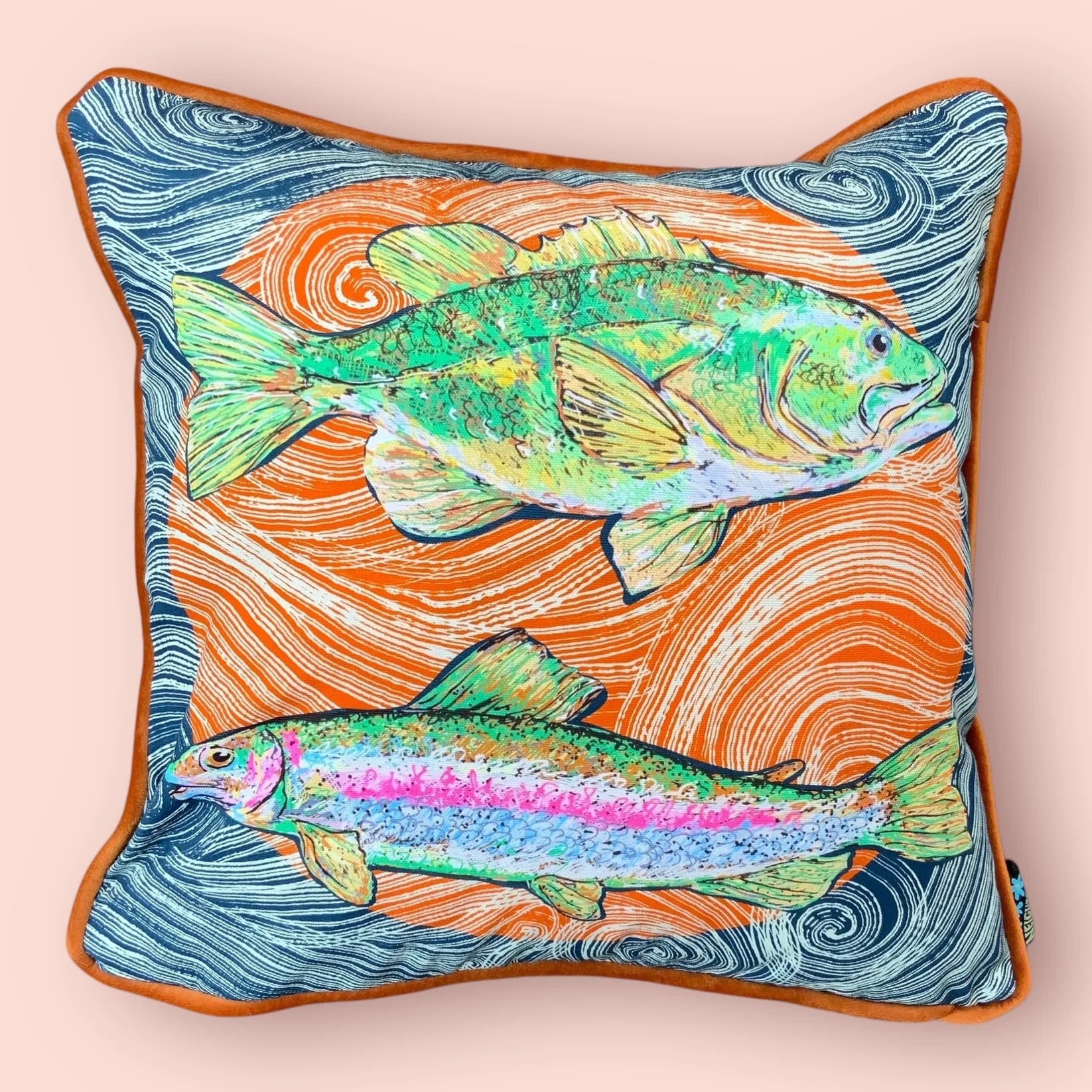 Decorative cushion with fish illustration on a light pink background.