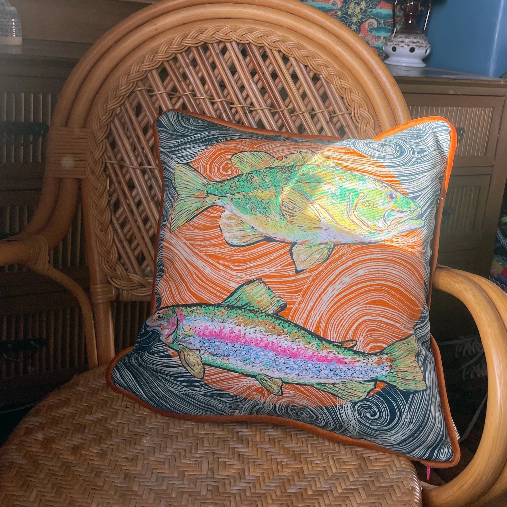 Decorative cushion with fish design on a wicker chair.