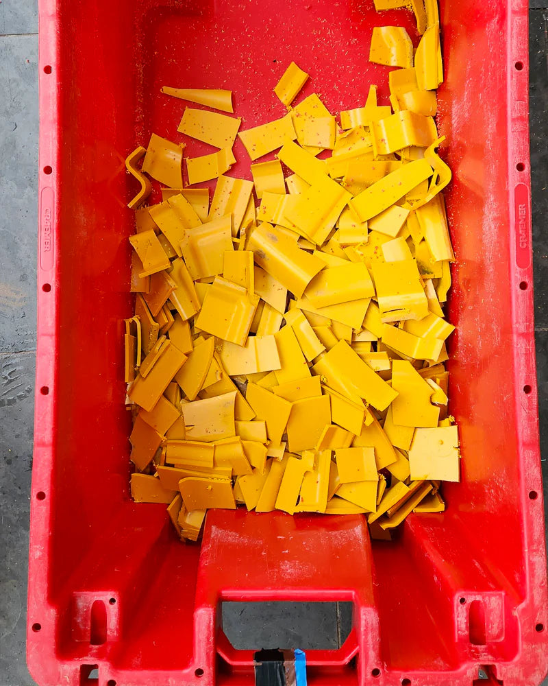Red container filled with yellow plastic on a grey floor.