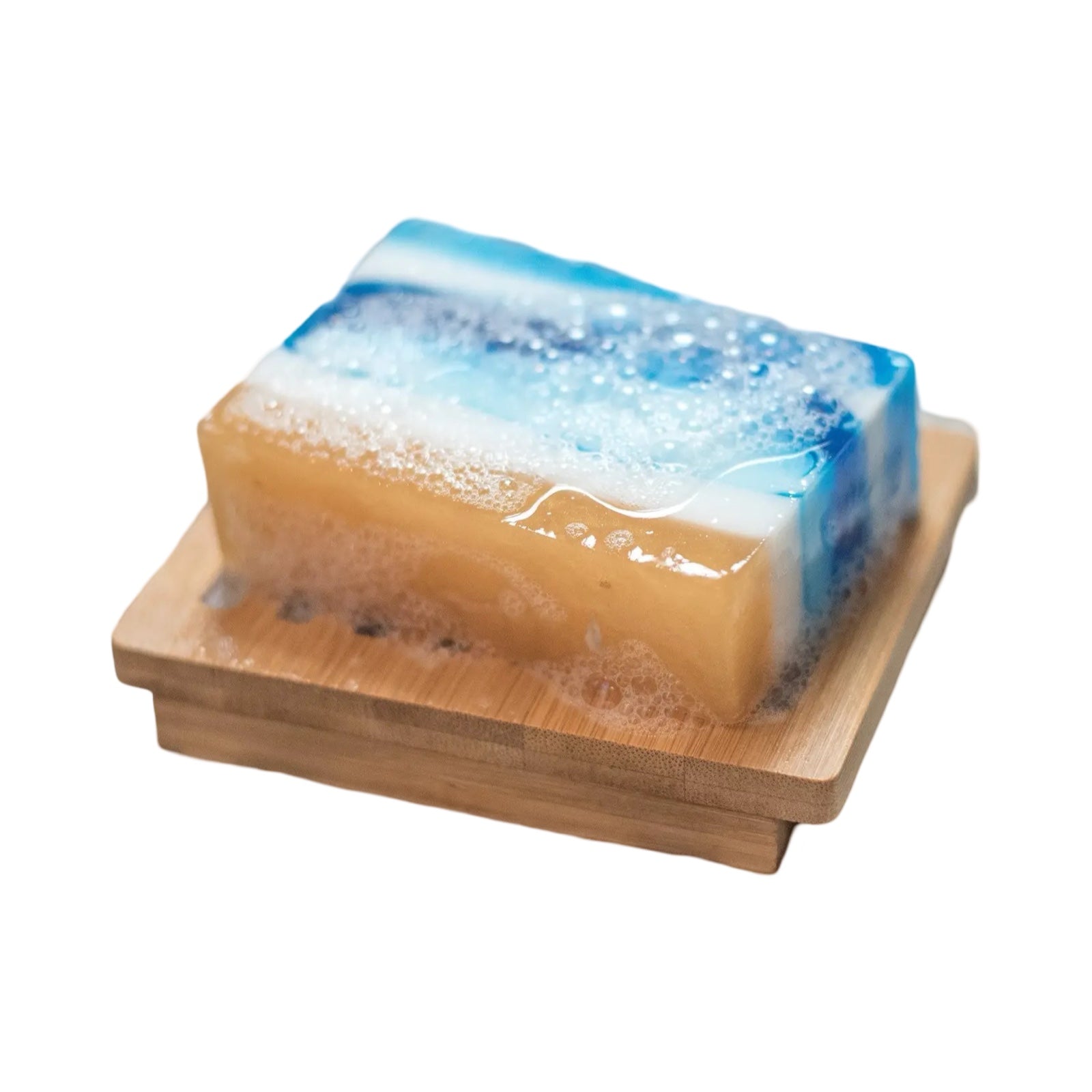 A bar of blue and white sea salt and driftwood soap sitting on a wooden soap dish.