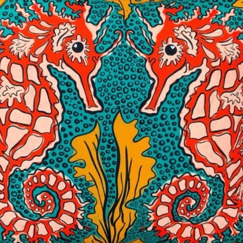 Colourful cushion cover featuring a pair of red and white seahorses against a green bubbly background with orange seaweed.