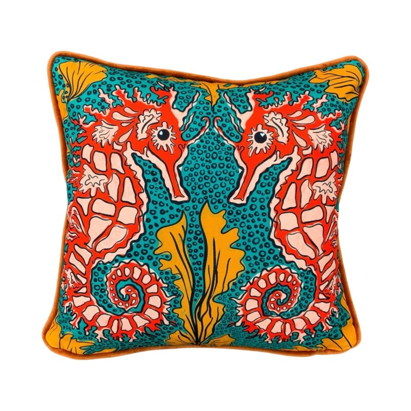 Colourful cushion featuring a pair of red and white seahorses against a green bubbly background with orange seaweed.