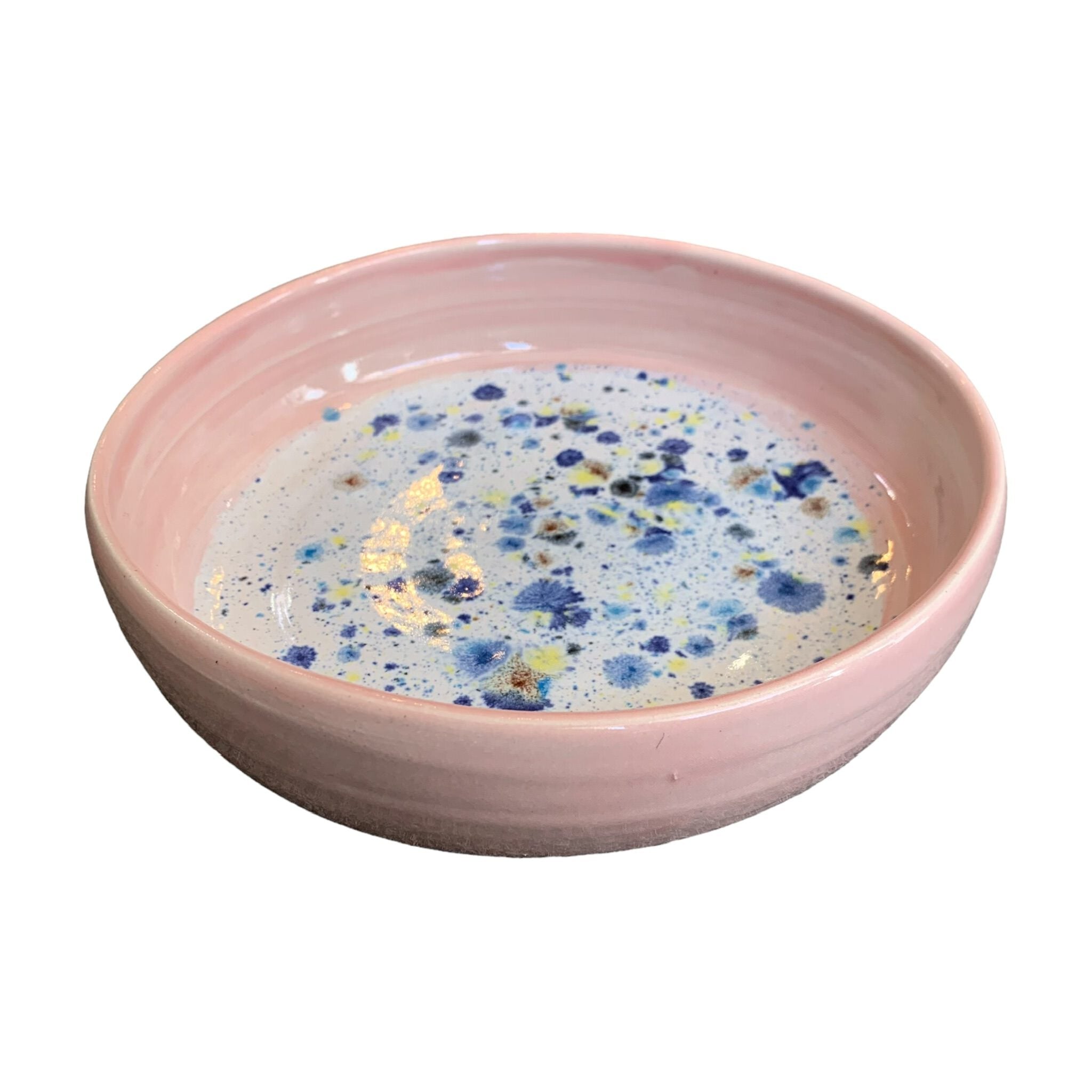 The side of a ceramic pasta bowl with a pink edge and a navy, yellow and white shoreline pattern in the centre.