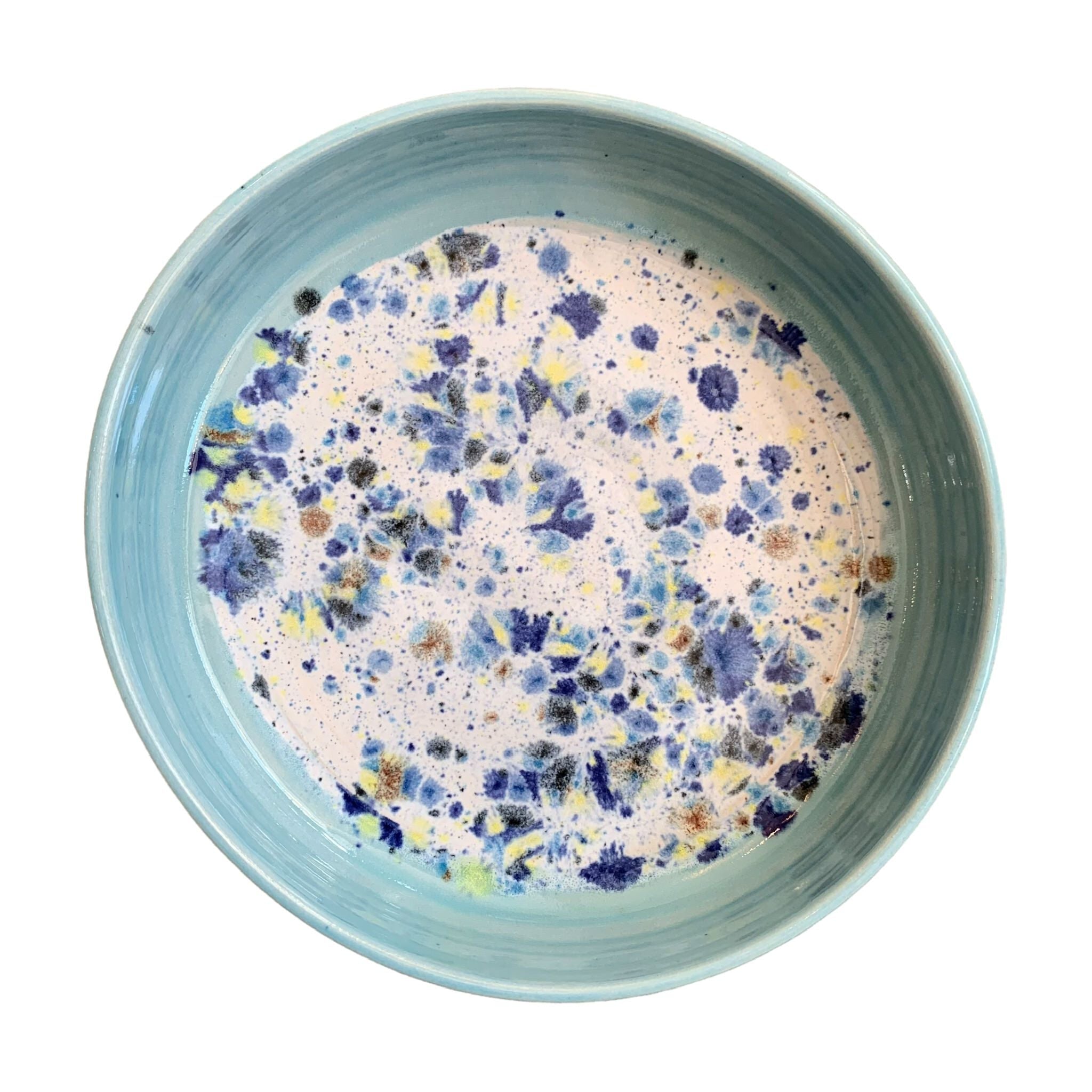 The top of a ceramic pasta bowl with a turquoise edge and a navy, yellow and white shoreline pattern in the centre.