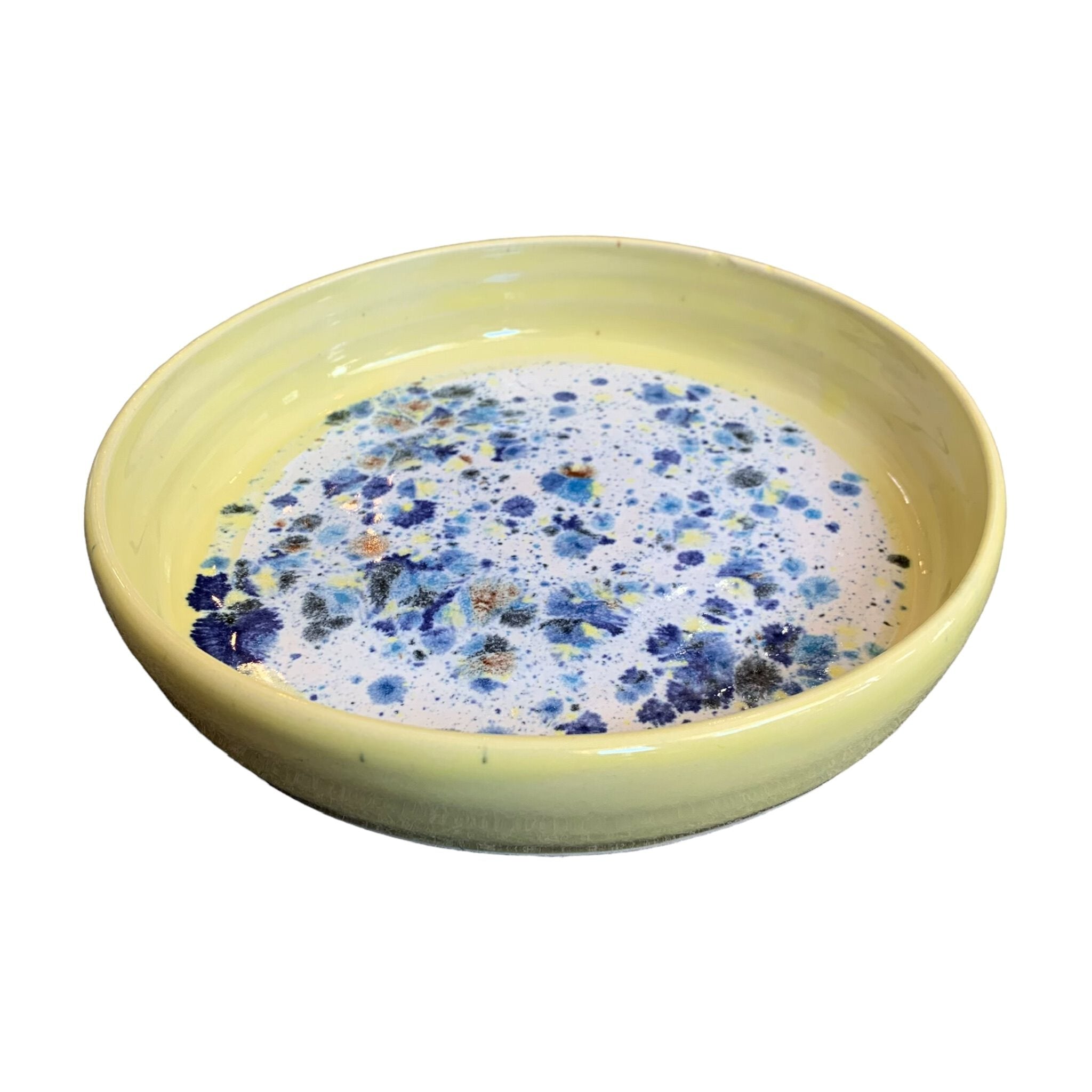 The side of a ceramic pasta bowl with a yellow edge and a navy, yellow and white shoreline pattern in the centre.