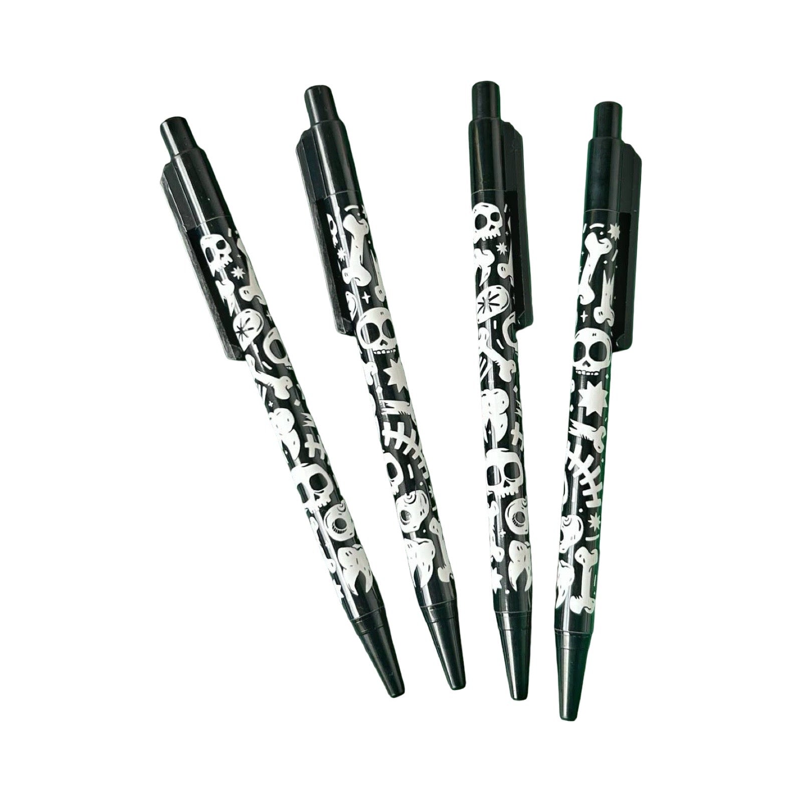 Four ballpoint pens with black background and white skull and crossbones patterns, on a plain white background.