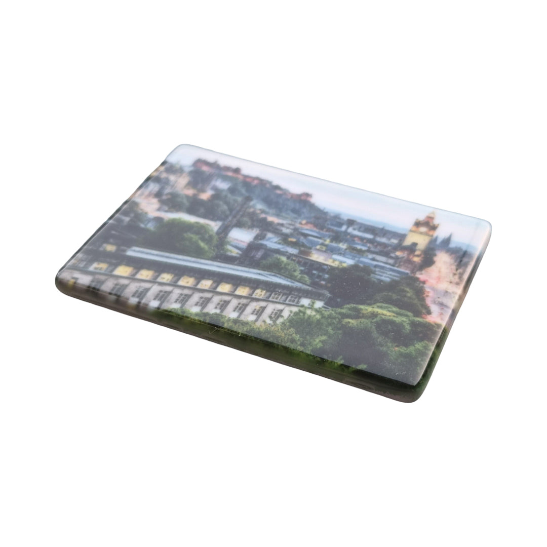 A ceramic magnet with a picture of Edinburgh on it.