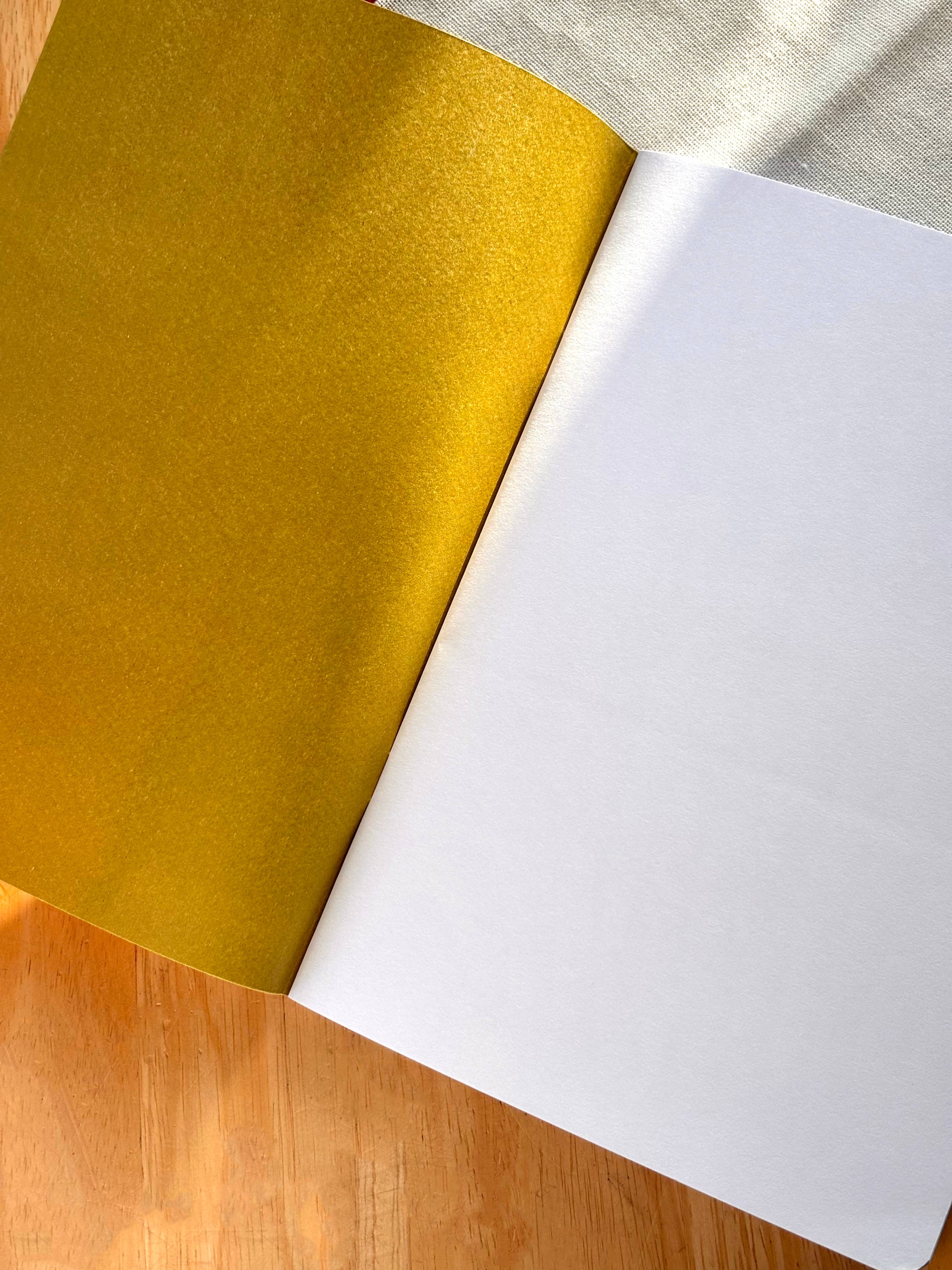 Notebook with one yellow and one white, on a wooden surface.