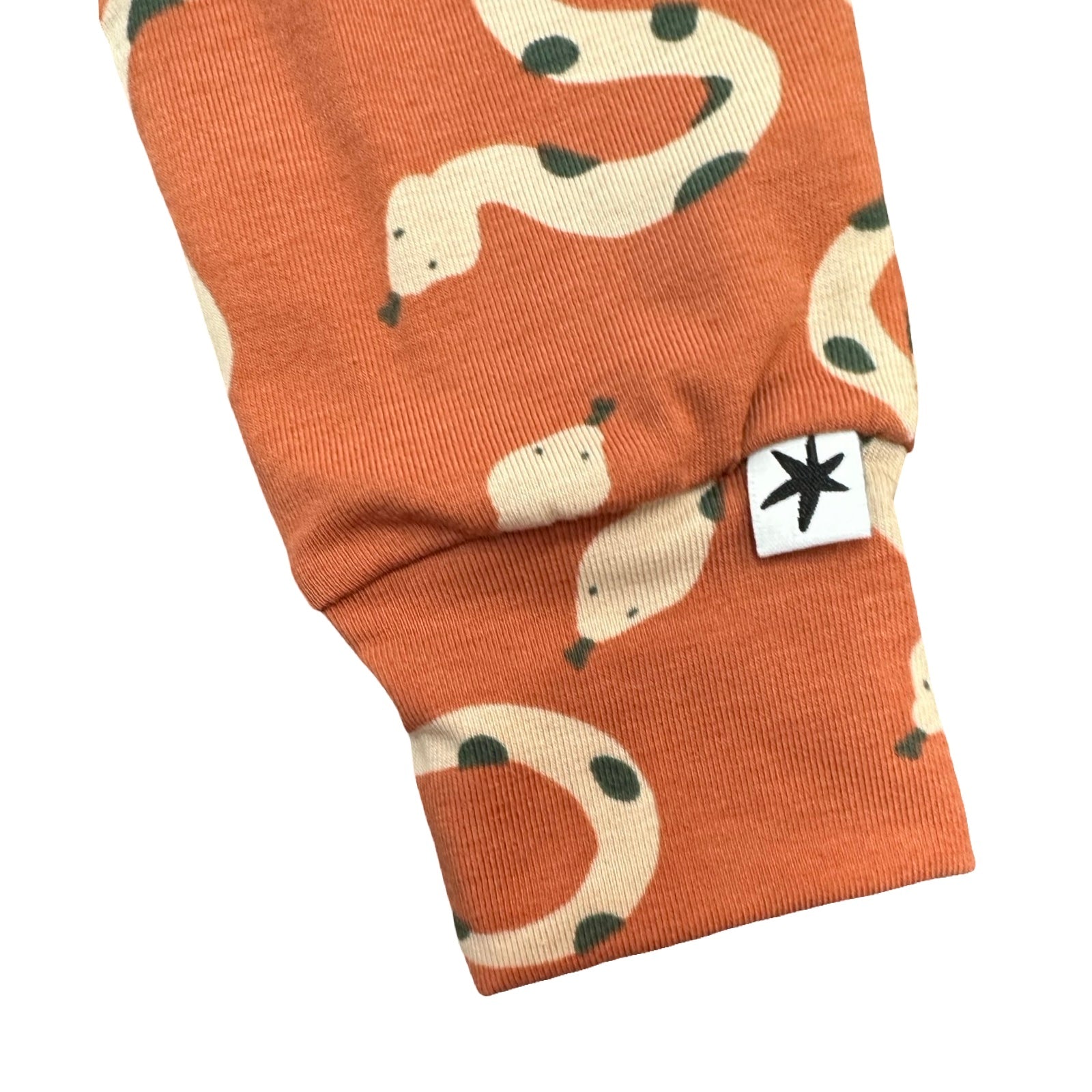 Orange fabric with snake pattern and a white label on a white background.