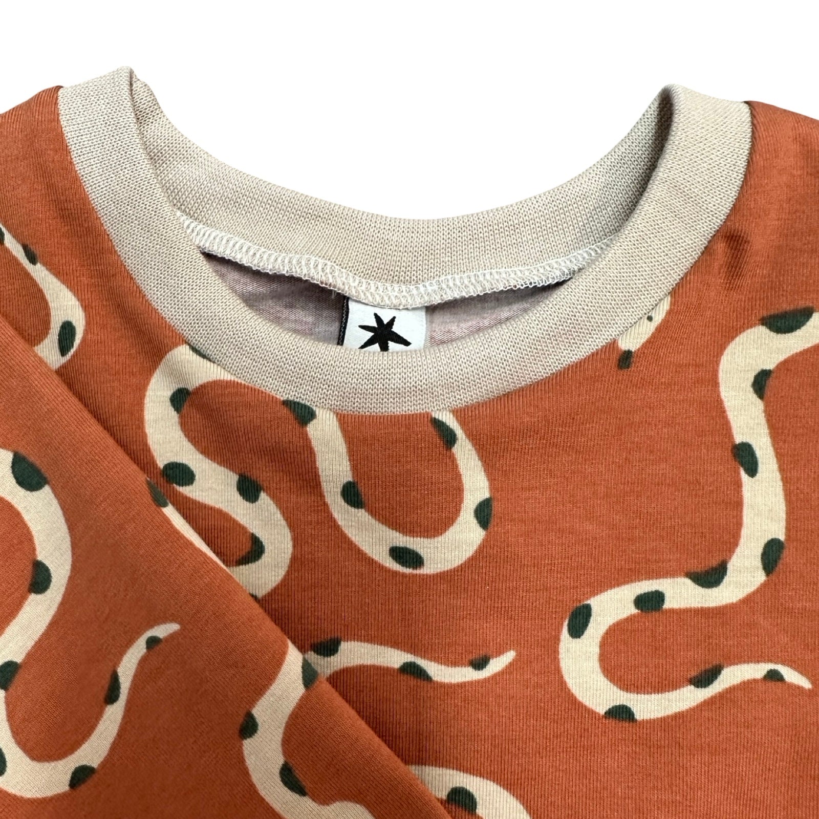 Close-up of a orange garment with snake pattern and brand label.