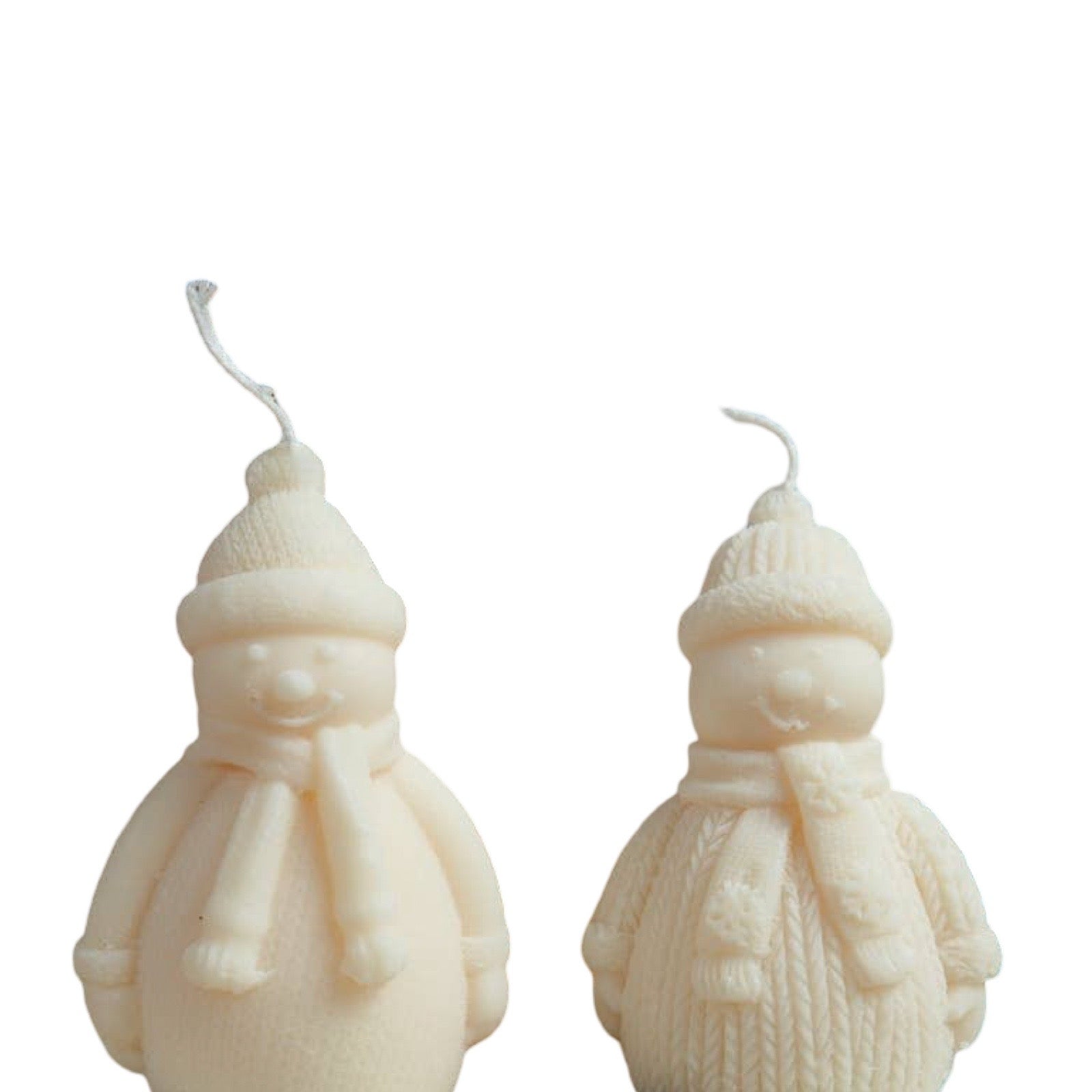 Two cream-colored snowman candles with textured knit hats, scarves, and wicks, shown against a plain white background.