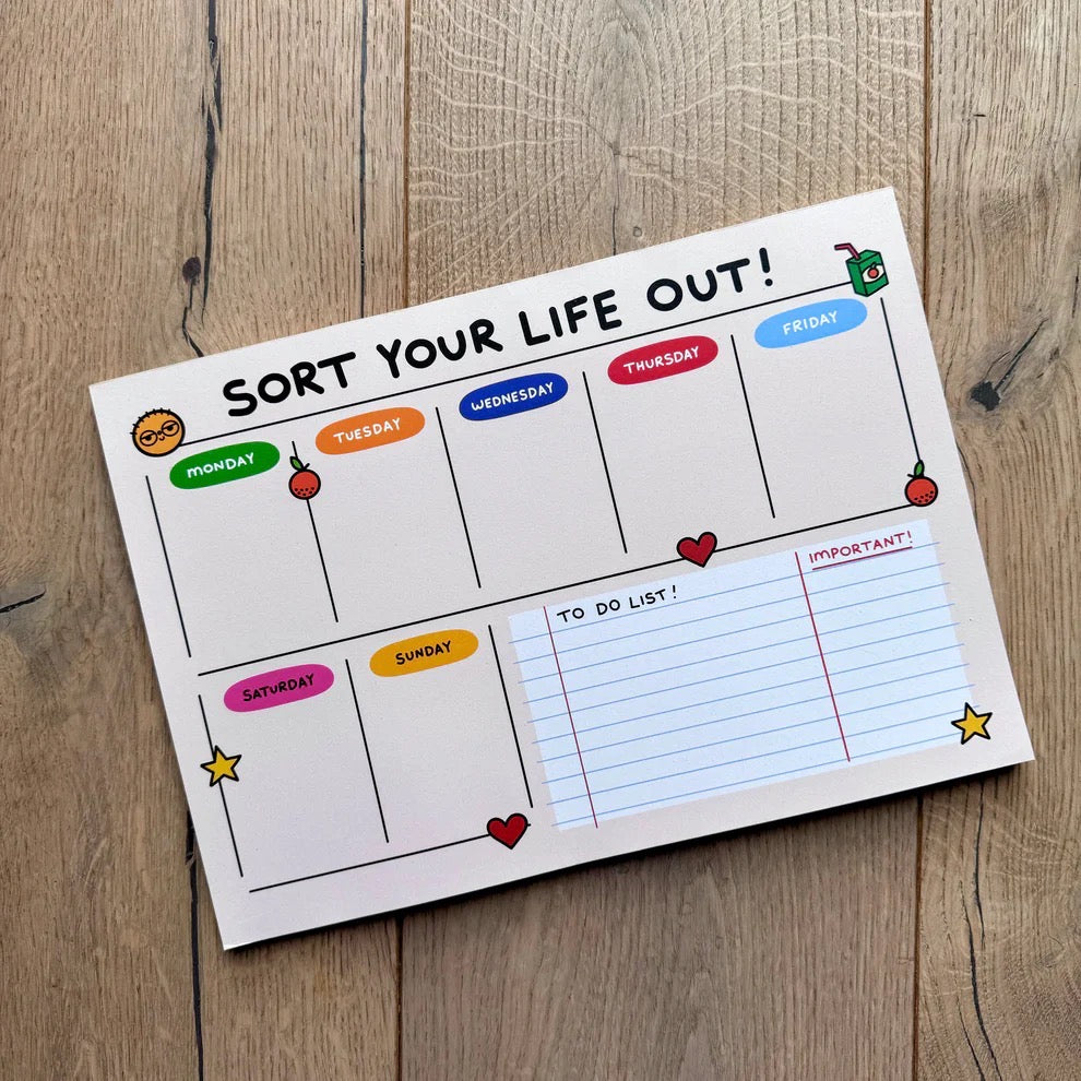 Weekly planner with colourful days of the week labels on a wooden surface.