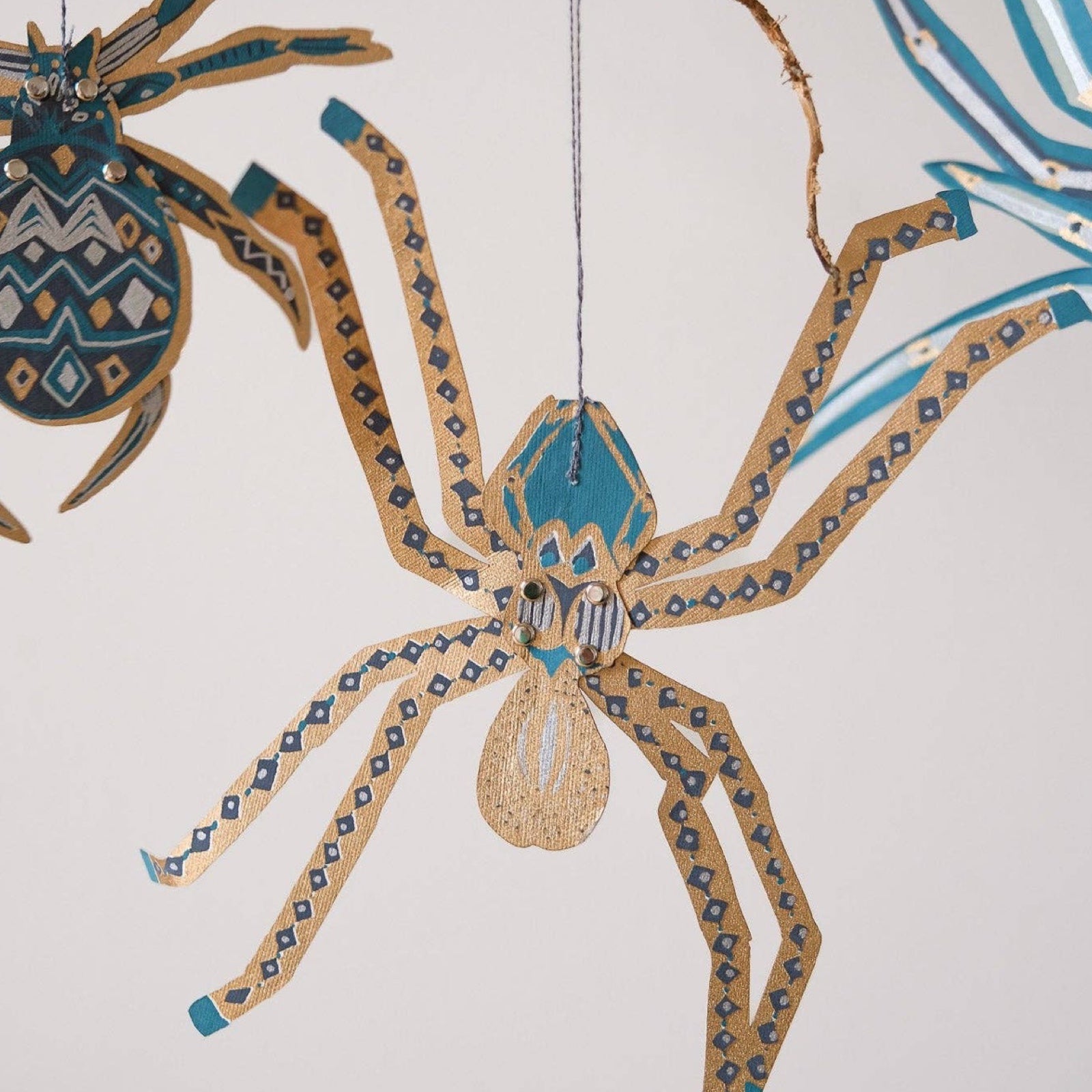 A paper hanging spider decoration in teal and gold.