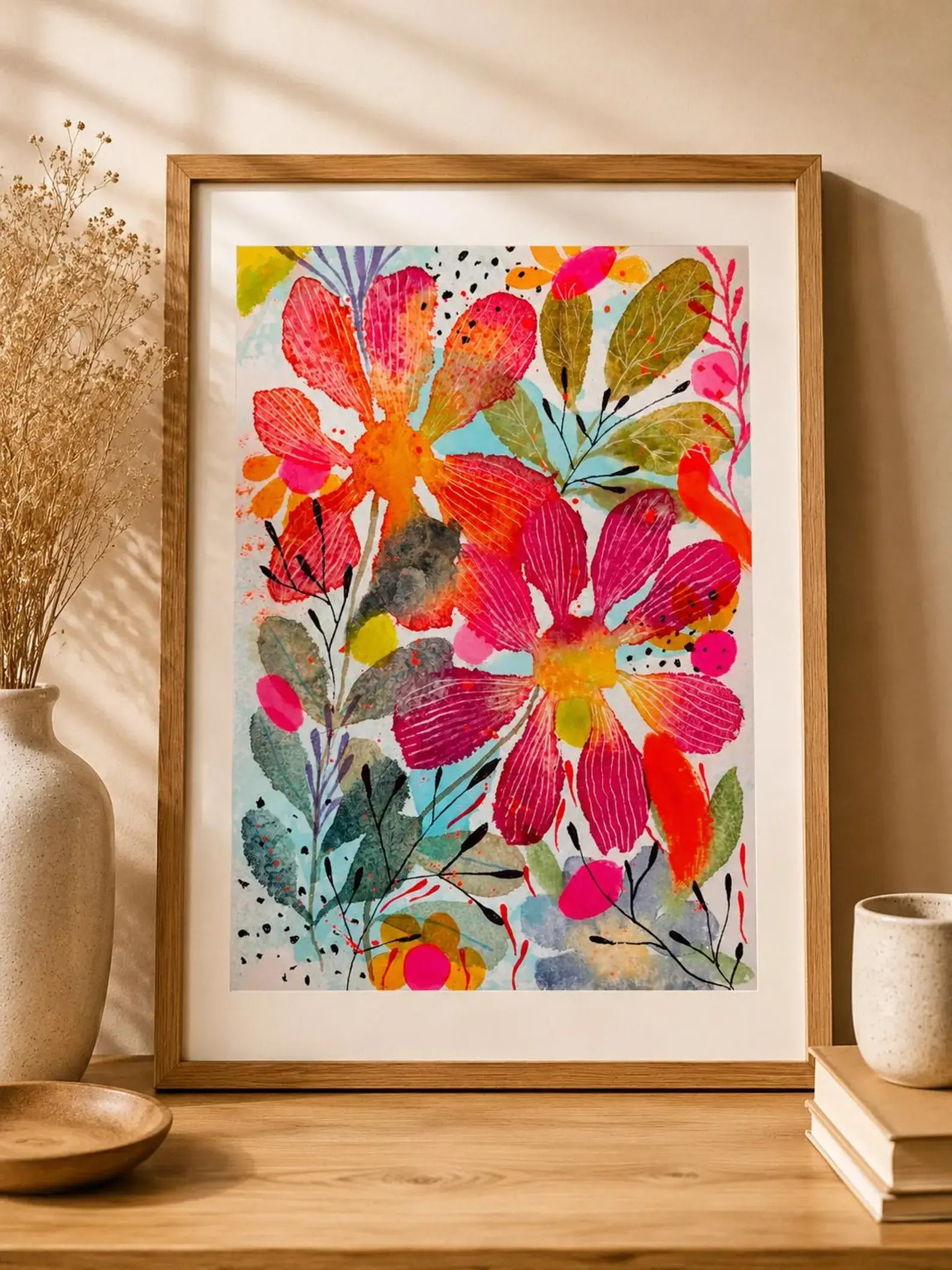 Framed colourful floral artwork on a wooden surface with a neutral background