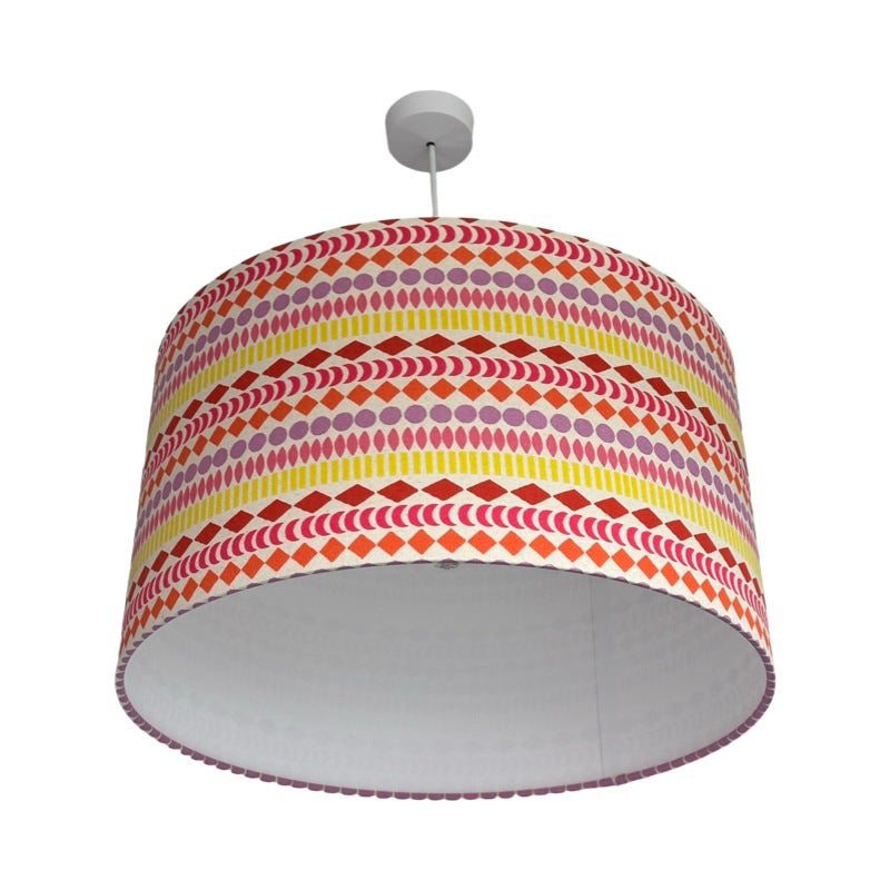 drum lampshade covered in cream canvas fabric with stripes of circles, diamonds, moons and ovals in yellow, pink, orange, lilac and red