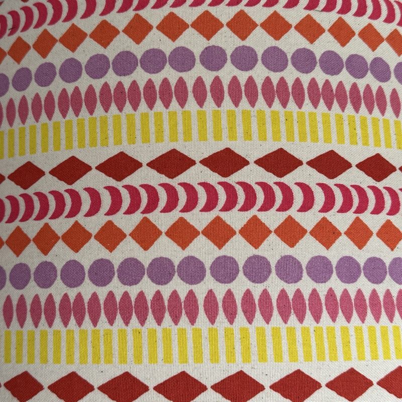 Cream canvas fabric with stripes of circles, diamonds, moons and ovals in yellow, pink, orange, lilac and red