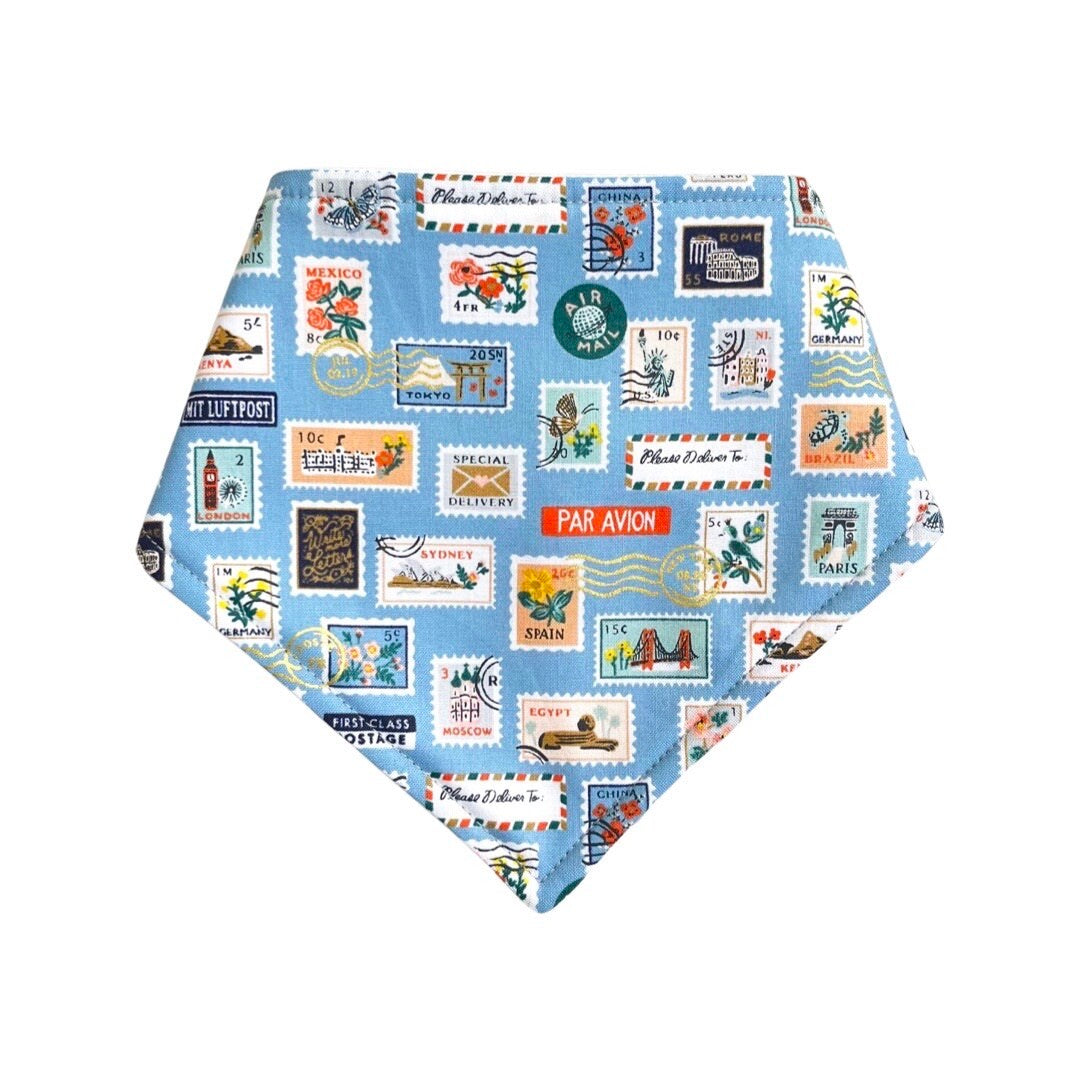 A blue bandana bib for babies with a stamp design, including various stamps.