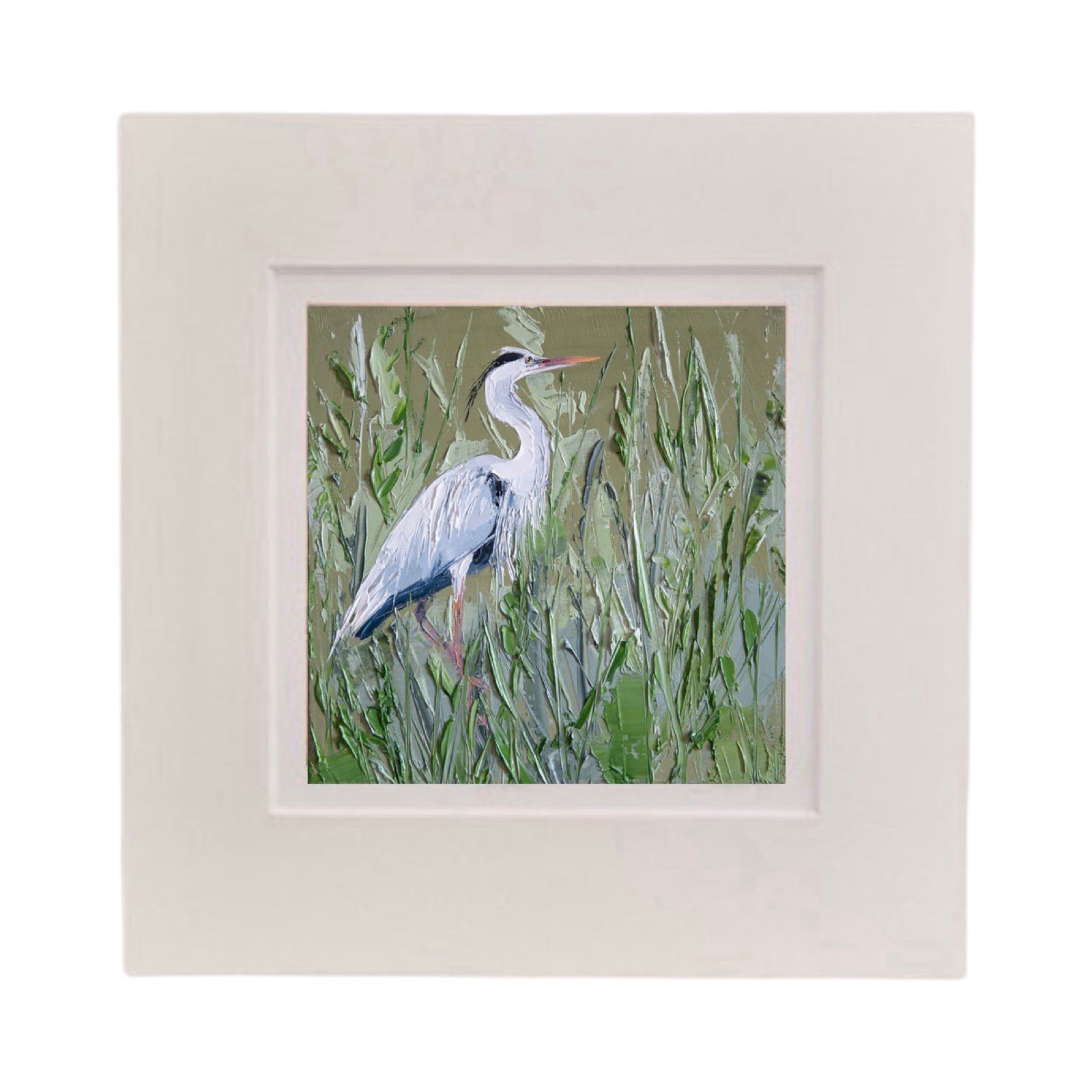 This square print features a heron standing in a field of long grass in a white cardboard mount.