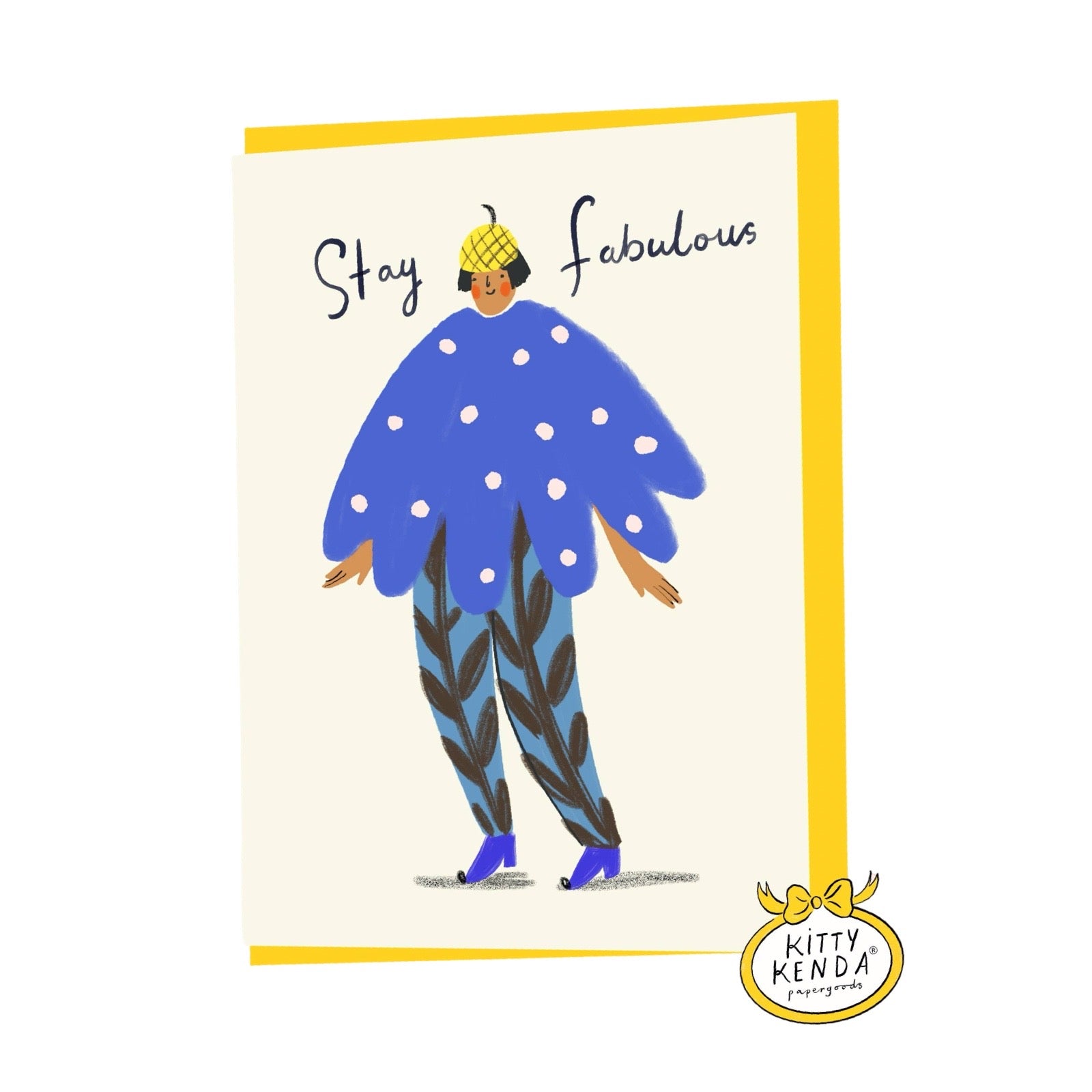 A greeting card featuring a whimsical illustration of a person in a blue polka-dot cape and patterned pants, with the text 'Stay Fabulous' on a cream background with a yellow border. A 'Kitty Kenda' brand sticker is visible in the bottom right corner.