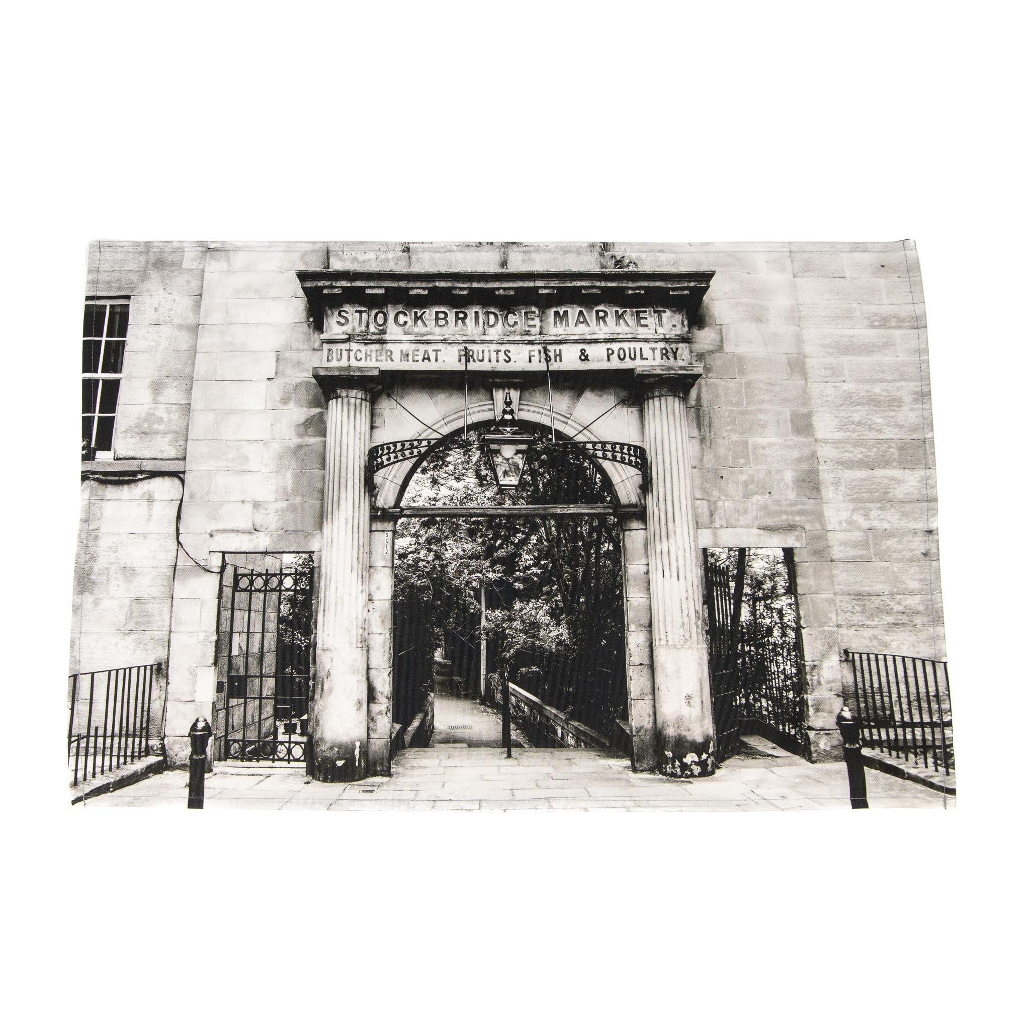 A tea towel with a black and white printed image of the Stockbridge Market Arch, Edinburgh.