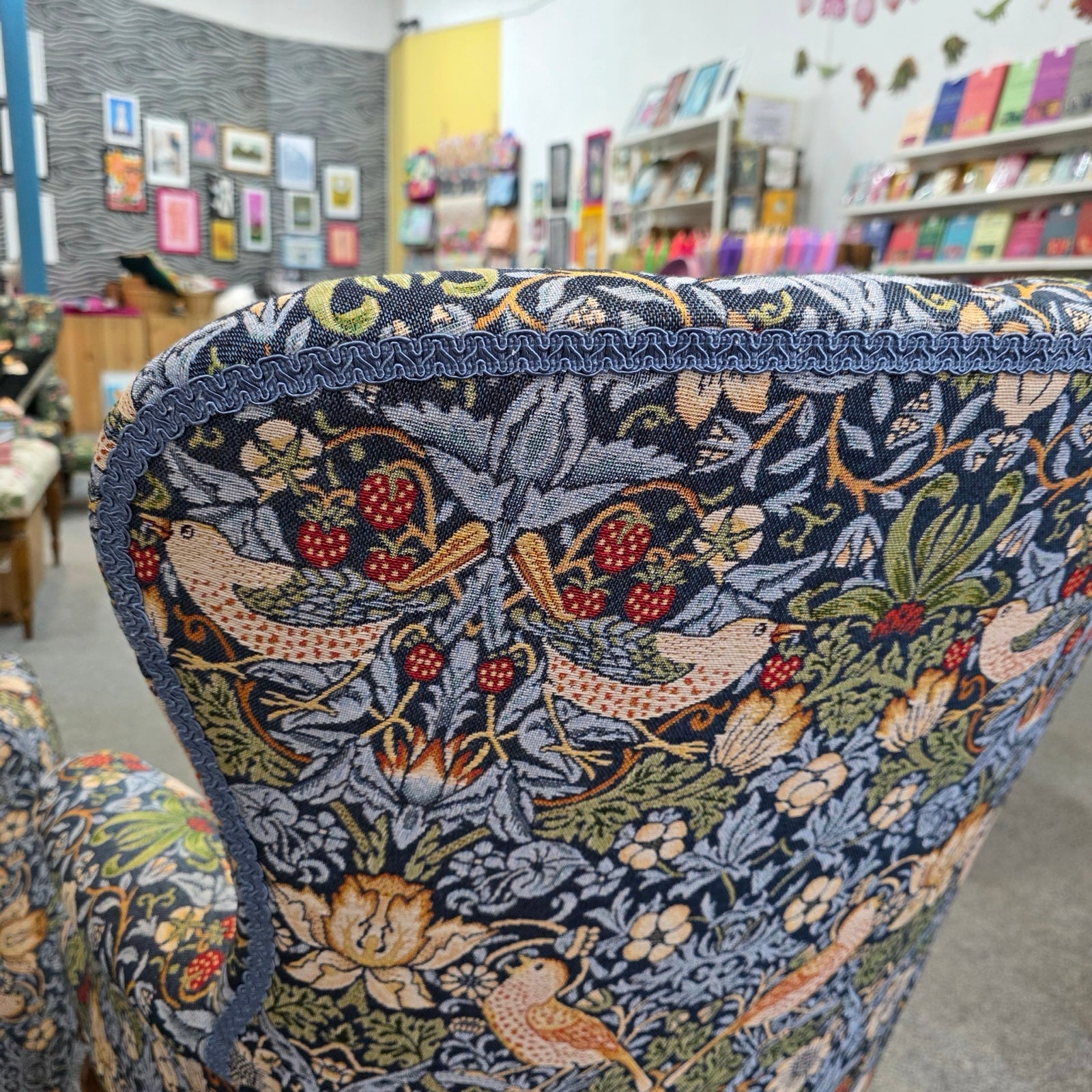 Chair with intricate floral and bird pattern in a store setting.