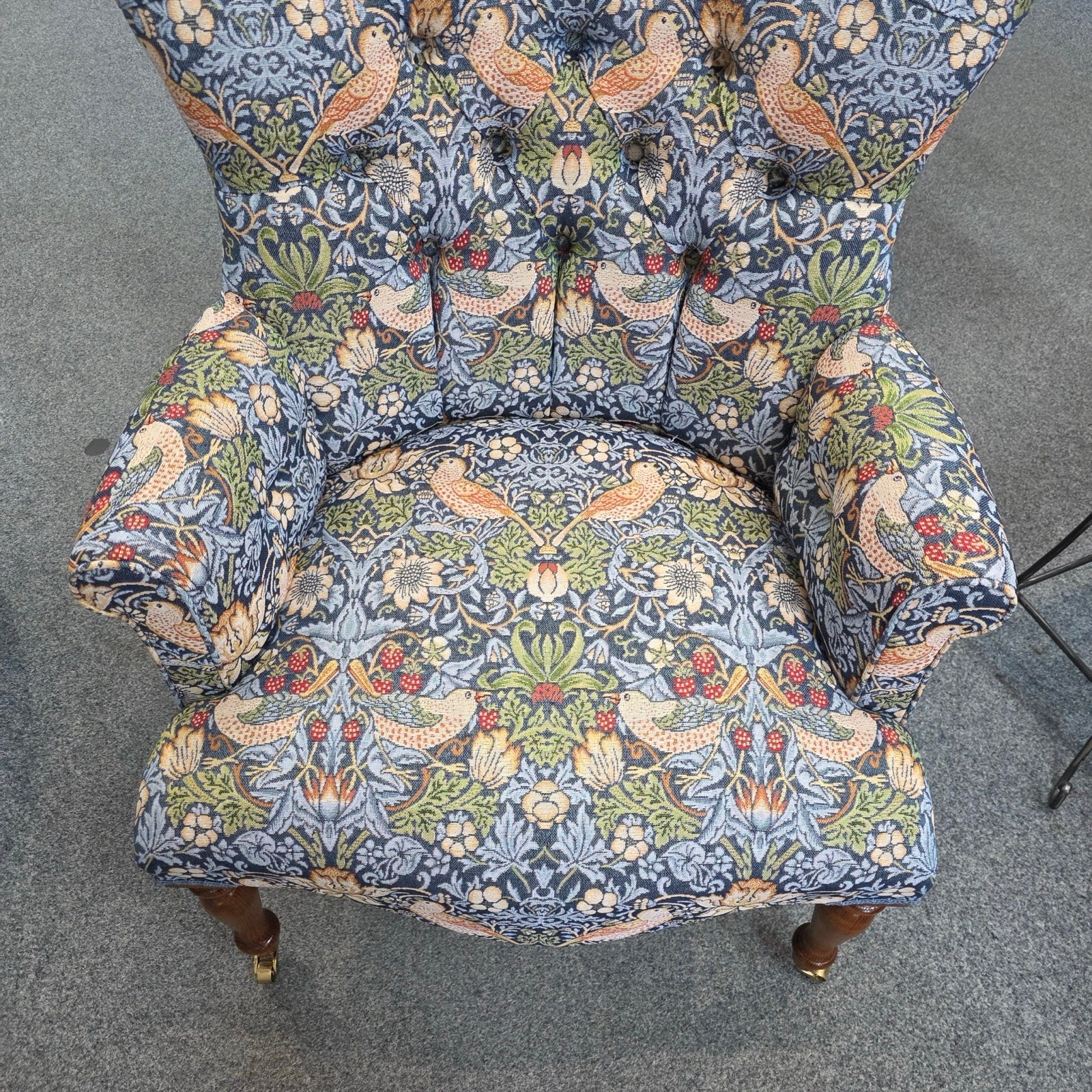 Decorative armchair with floral and bird pattern on a gray floor.