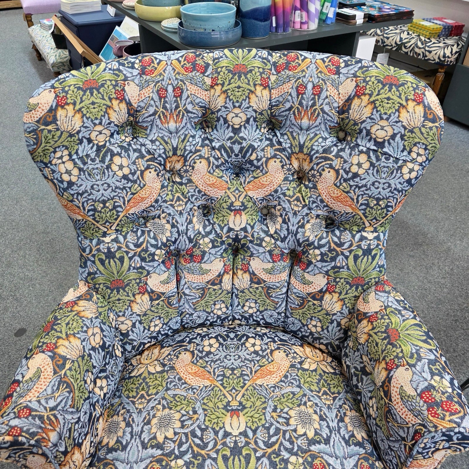 Decorative armchair with floral and bird pattern on a gray floor.