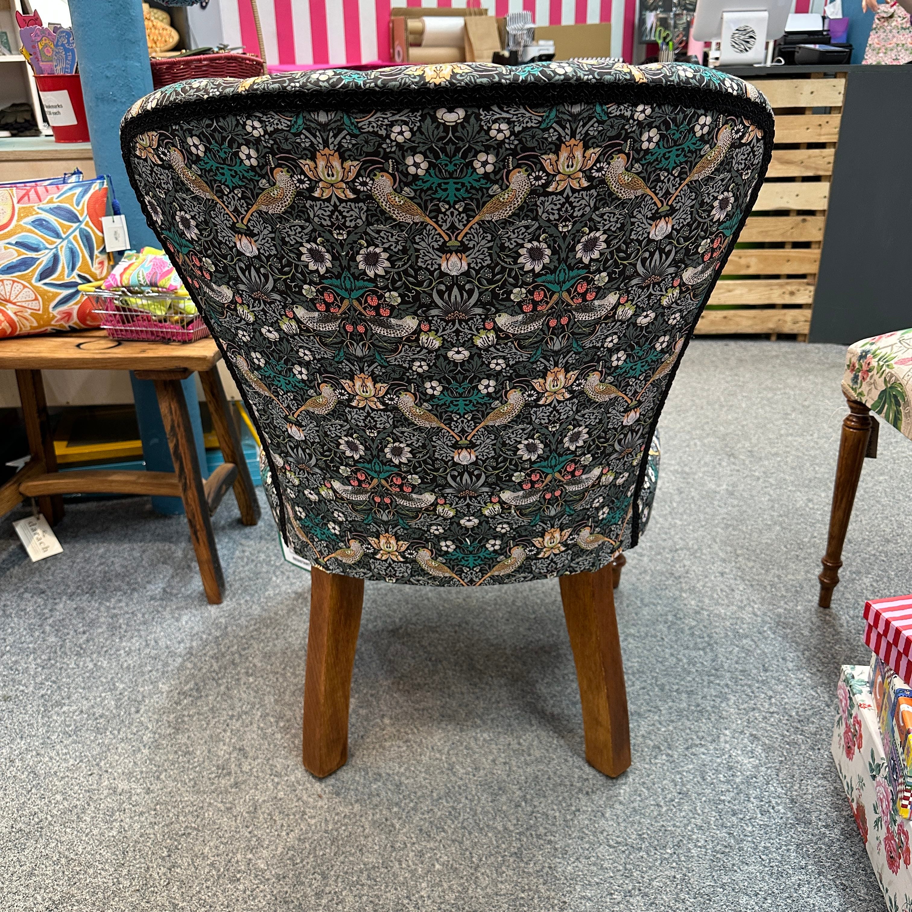 Chair with floral patterned fabric on a grey floor.