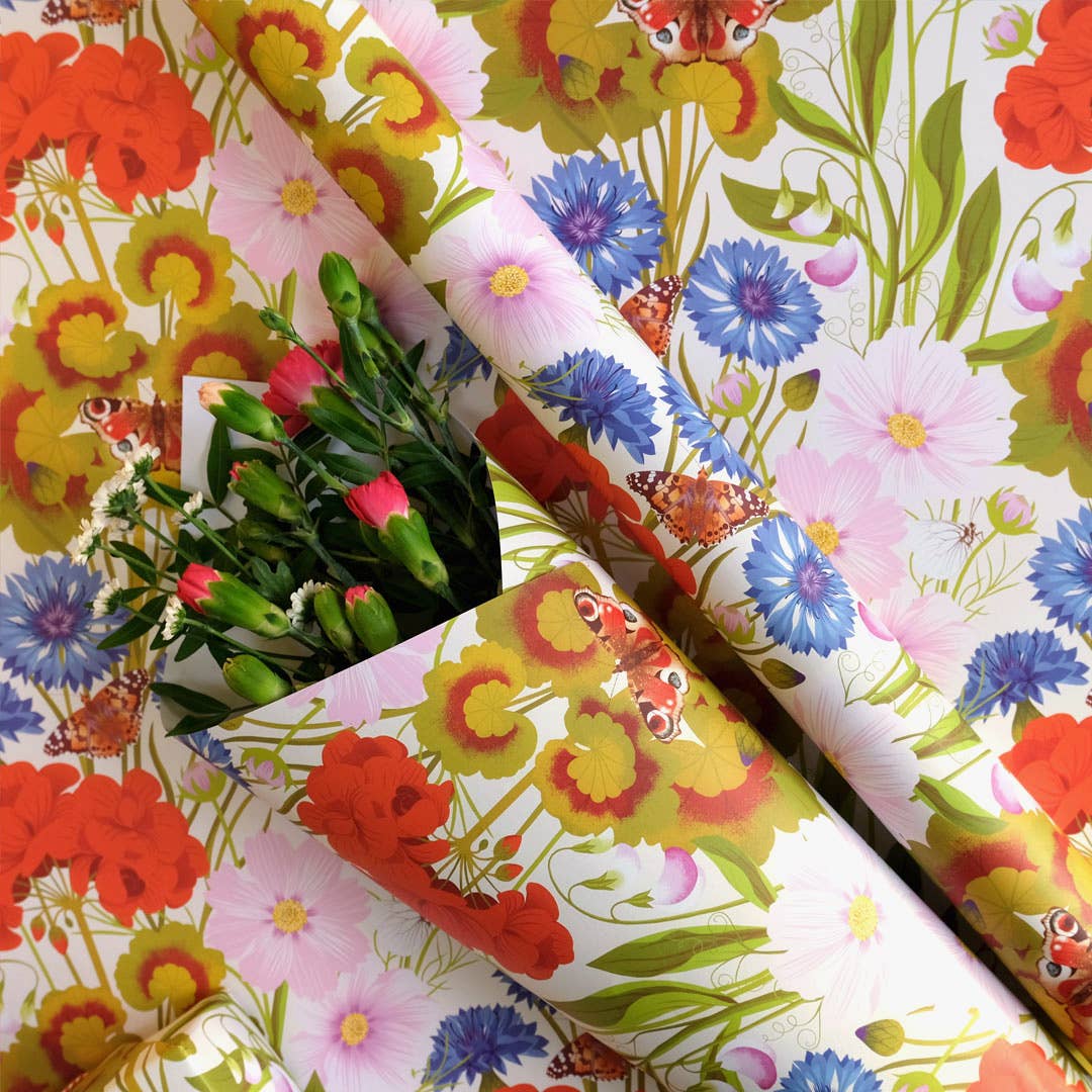 Colorful floral-patterned paper with flowers and butterflies, wrapped in a bundle of pink flowers.