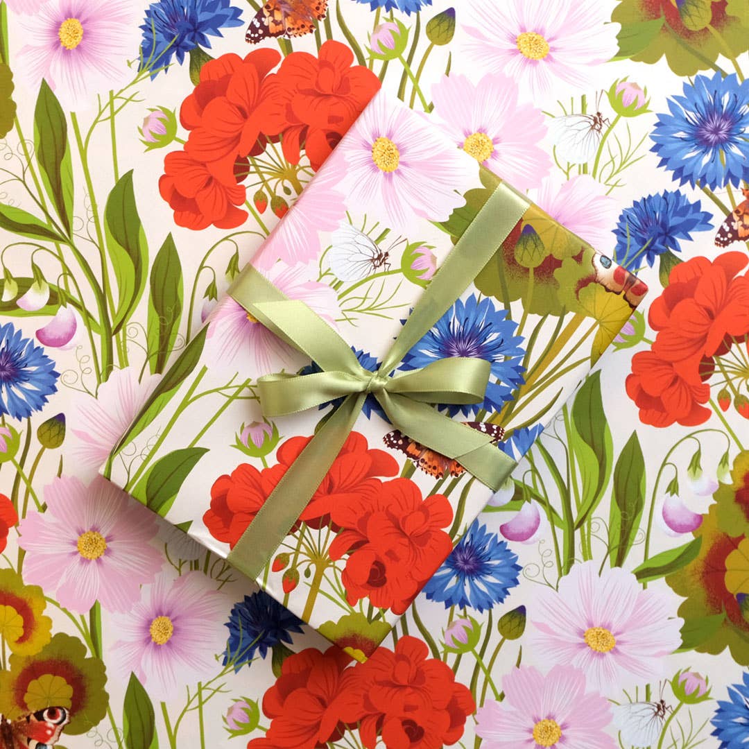 Gift box with a green ribbon on a floral wrapping paper.