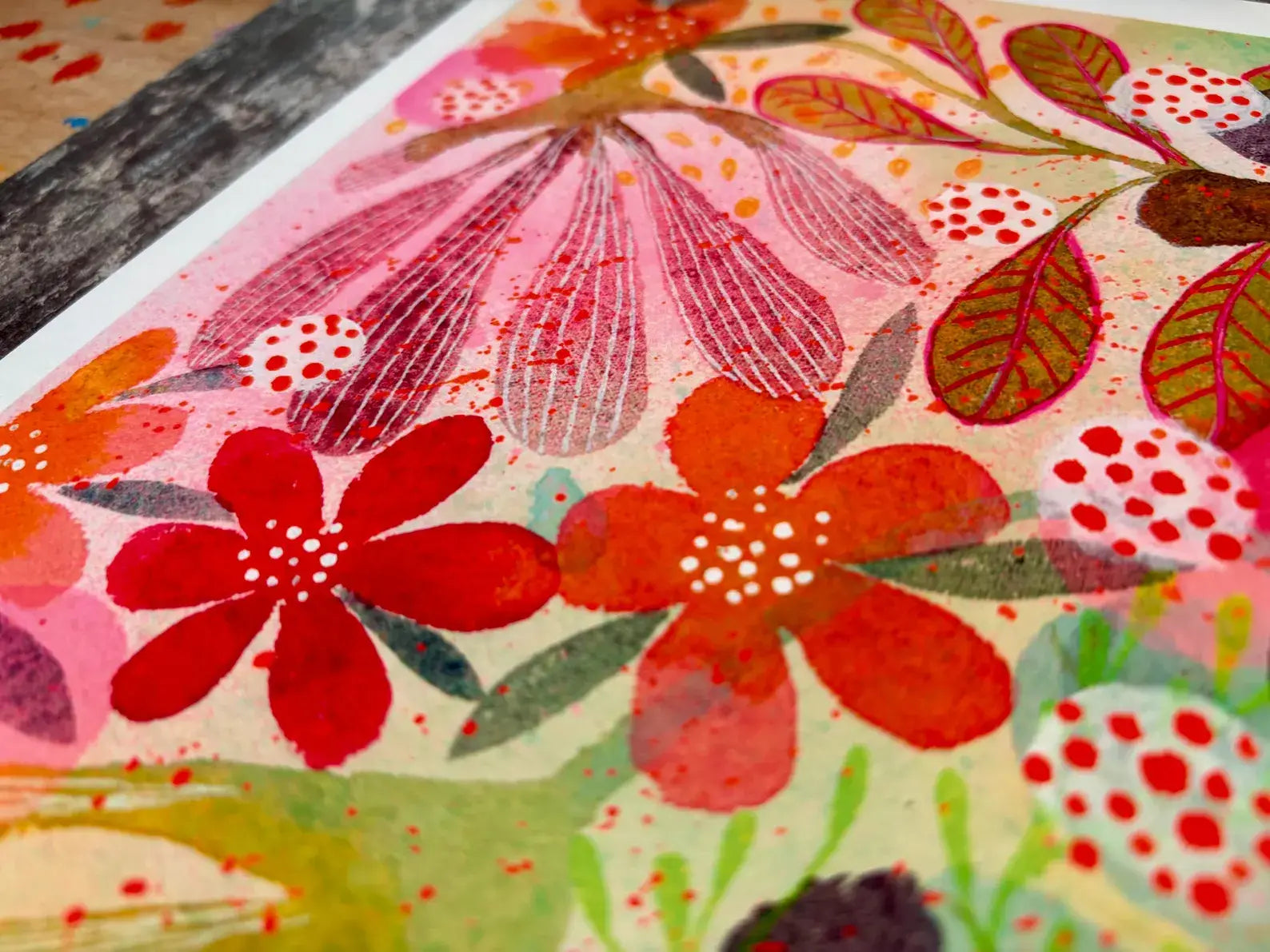 Colourful floral pattern with red, pink, and green flowers on a textured surface.