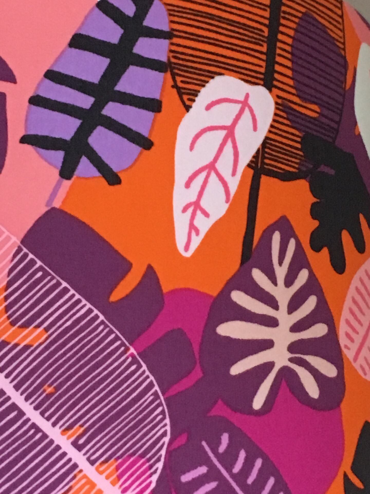 Orange fabric with a variety of pink, white, black and purple leaves.