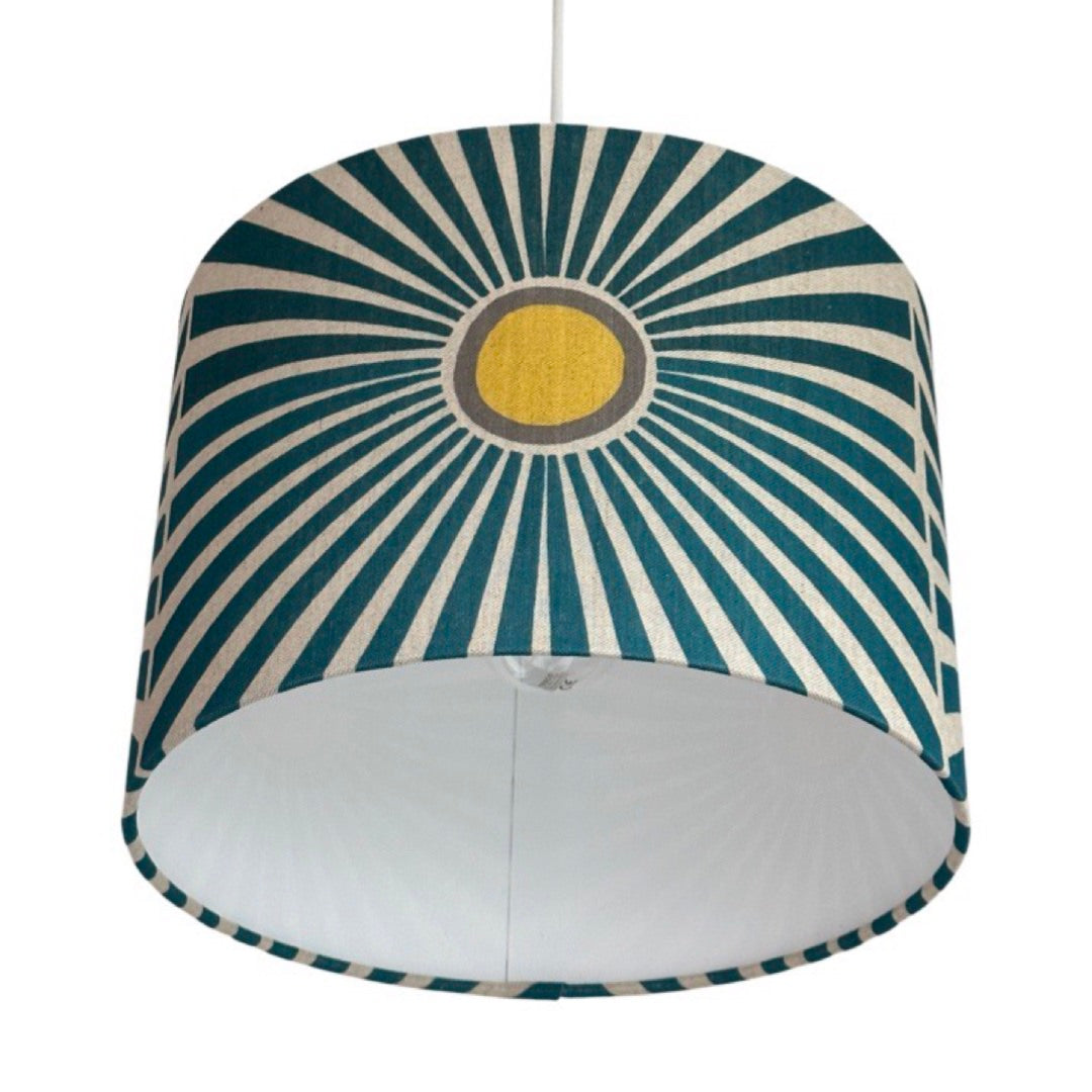 Close up of a drum lampshade in cream with yellow and grey suns and navy sunbeams